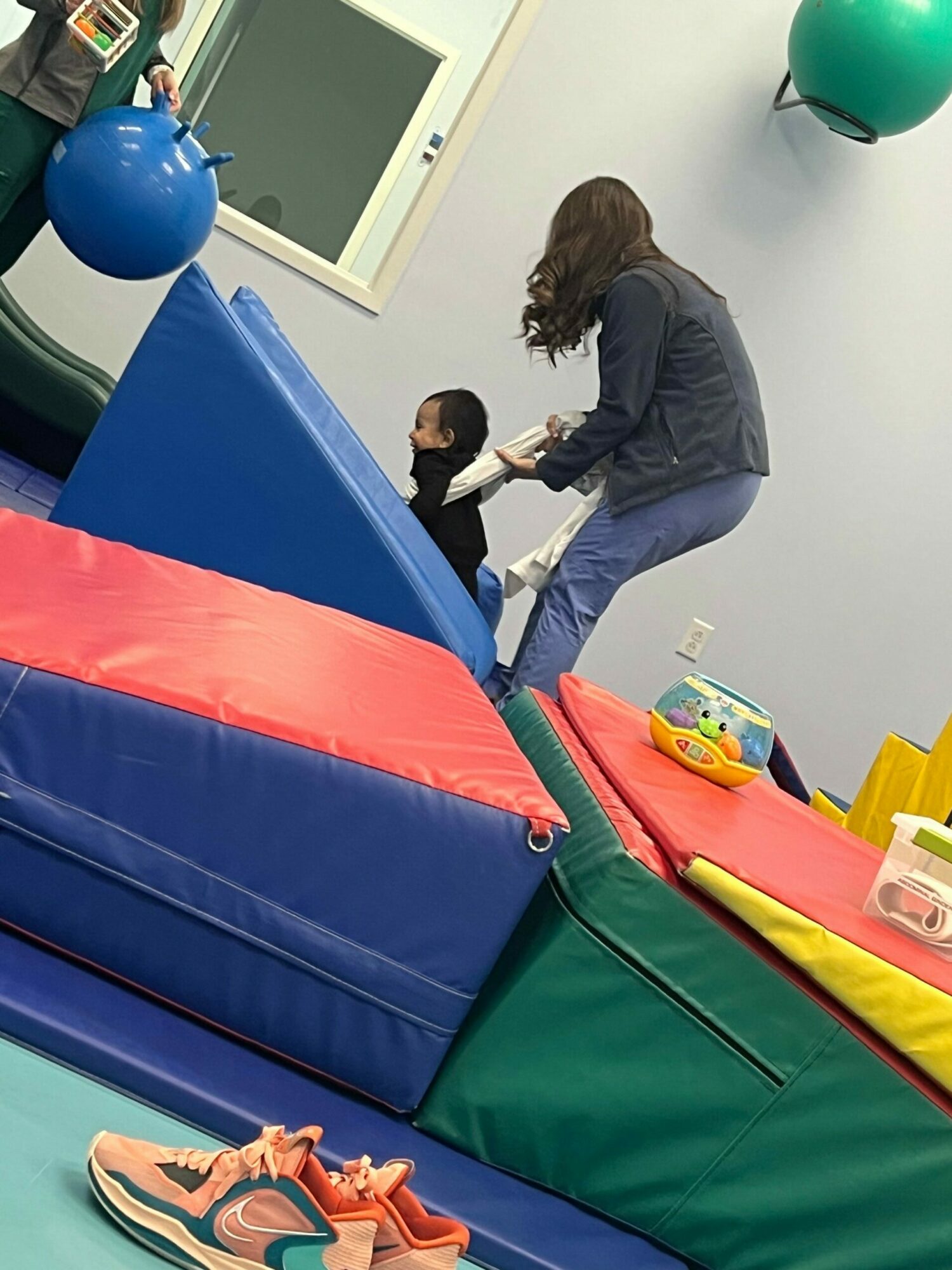 Children playing on colorful gym mats and foam blocks in an indoor play area.