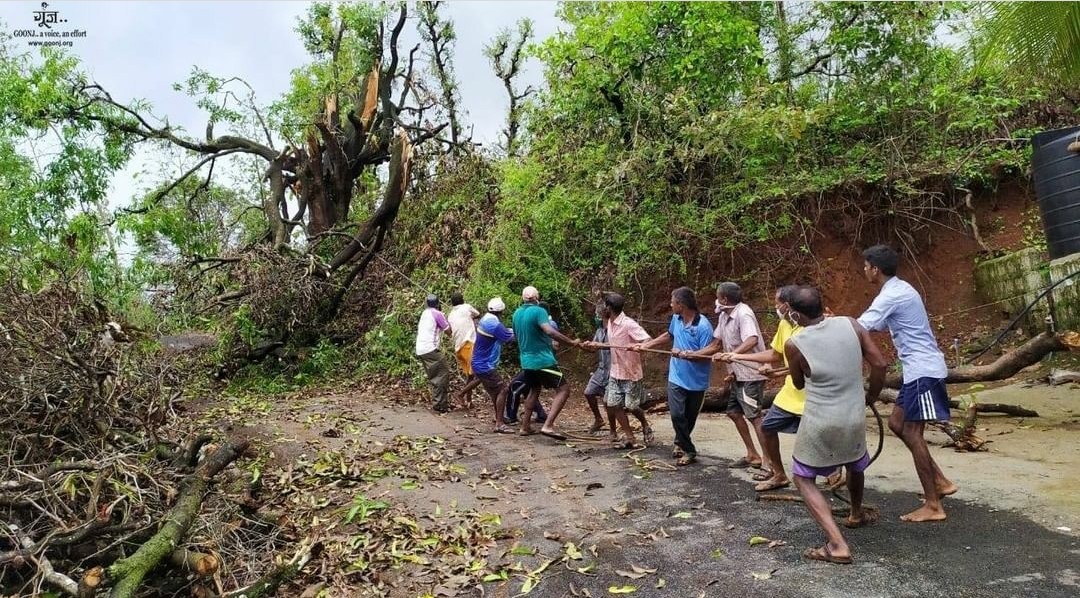 Group of children and adults walking along a dirt path surrounded by trees and greenery.
