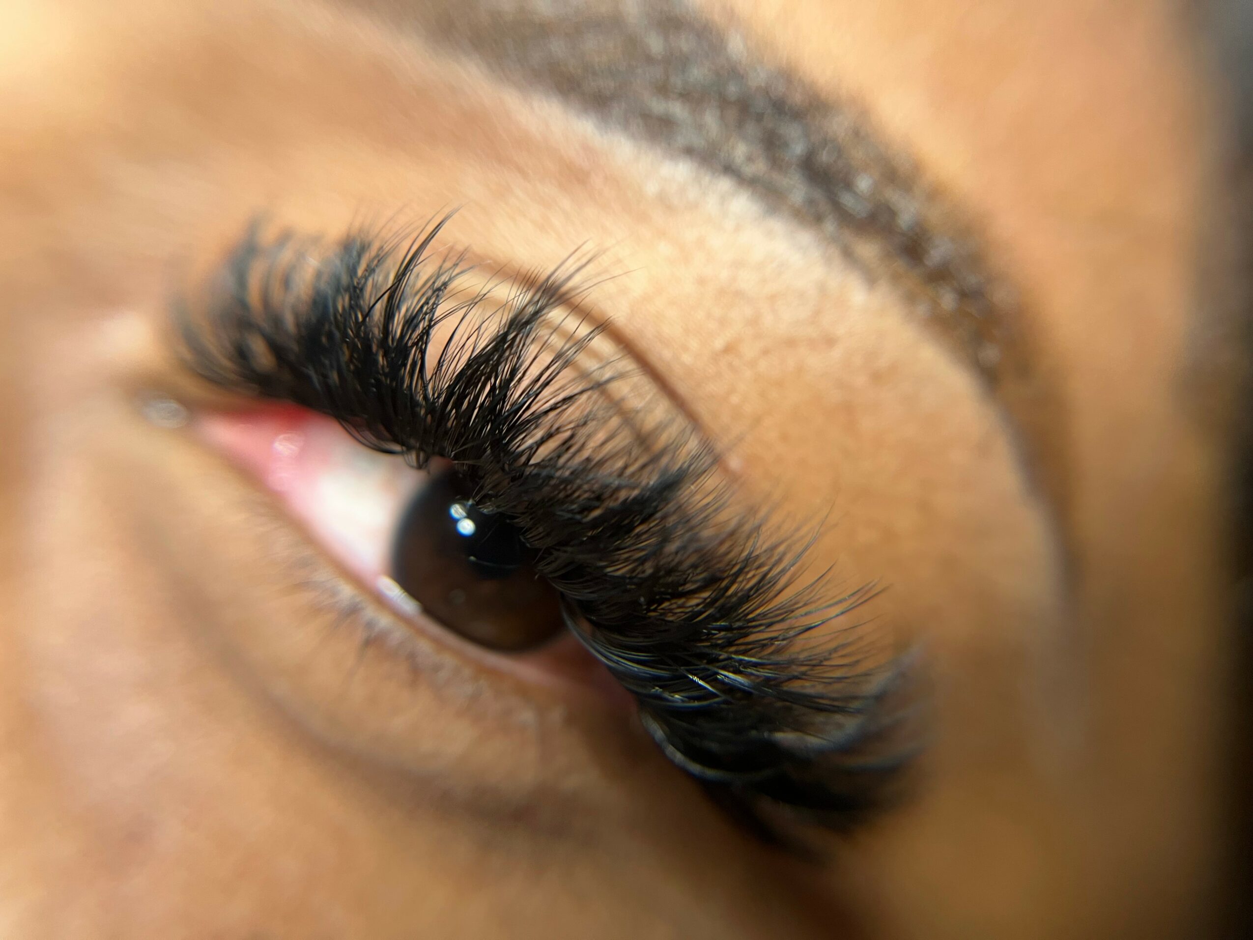 Close-up of a person's eye with long, thick eyelashes and well-defined eyebrow.