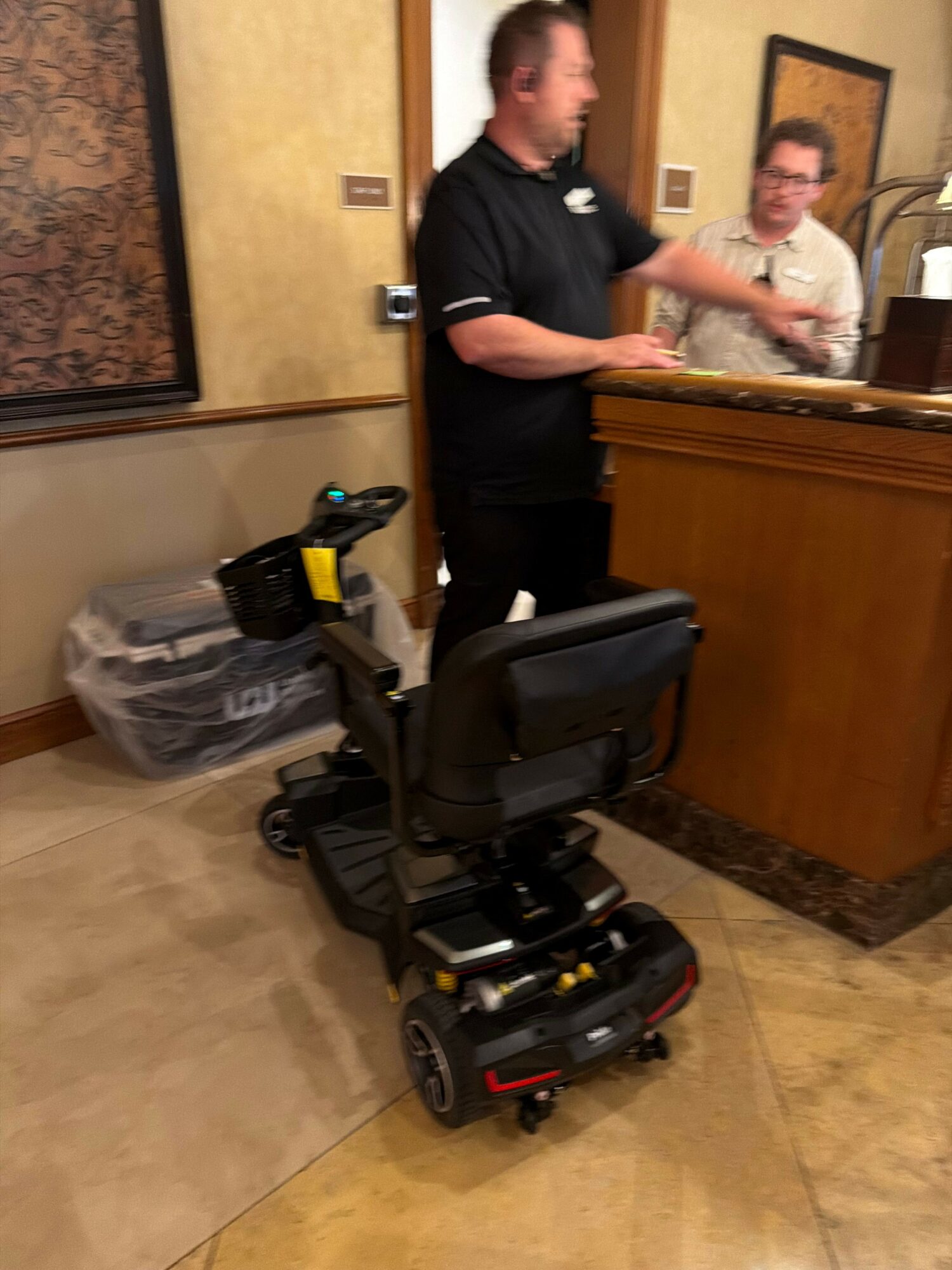 Person in black shirt operating cleaning machine in a room with wooden furniture and beige walls.