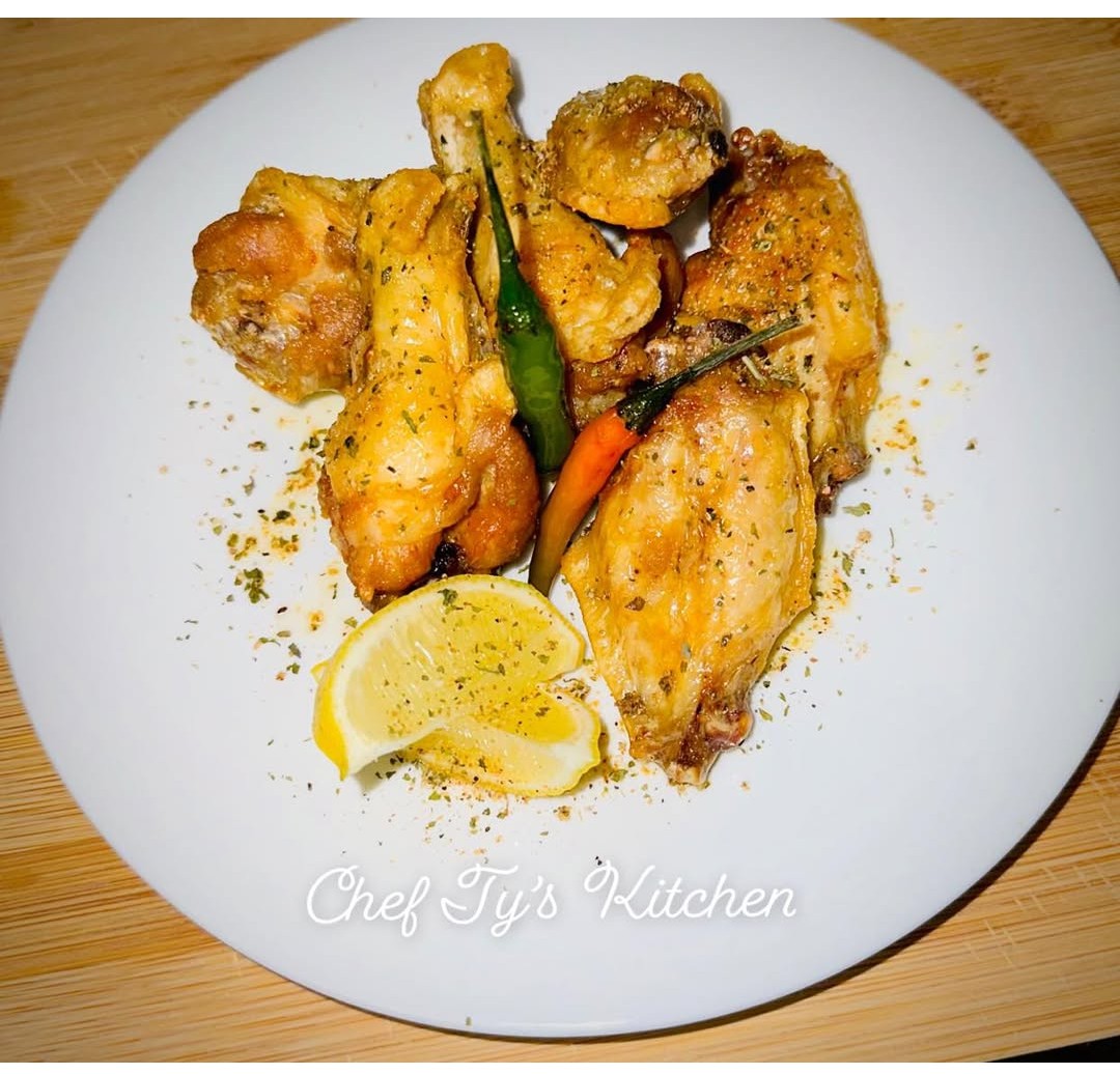 Plate with fried chicken, vegetables, lemon wedge, and seasoning, on a white dish with text 'Chef Ty's Kitchen'.
