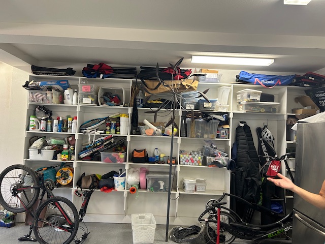 Shelves filled with various tools, equipment, and storage boxes in a garage or workshop.