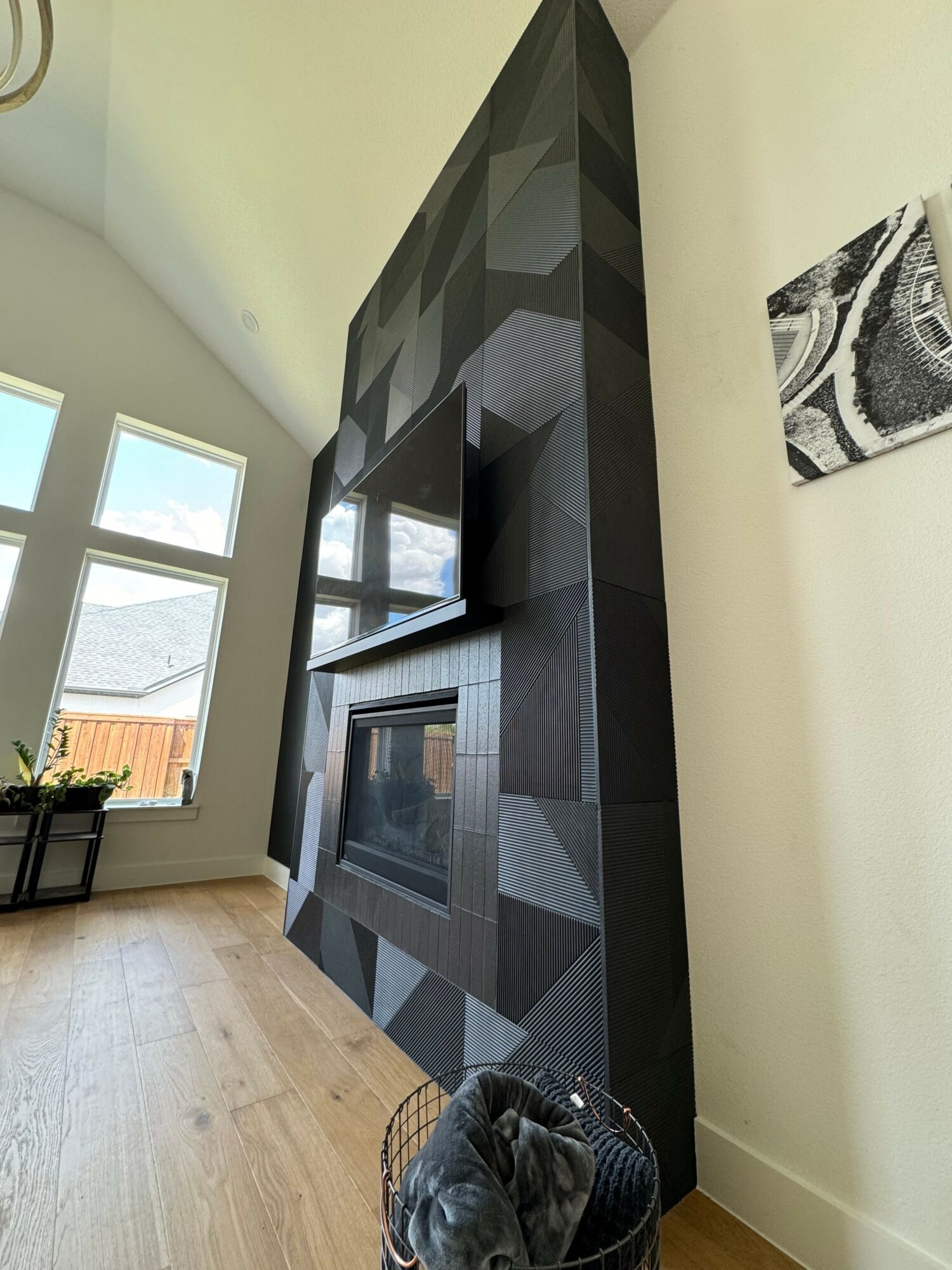 Corner of a room with a black geometric cabinet, a window, and a laundry basket with clothes.