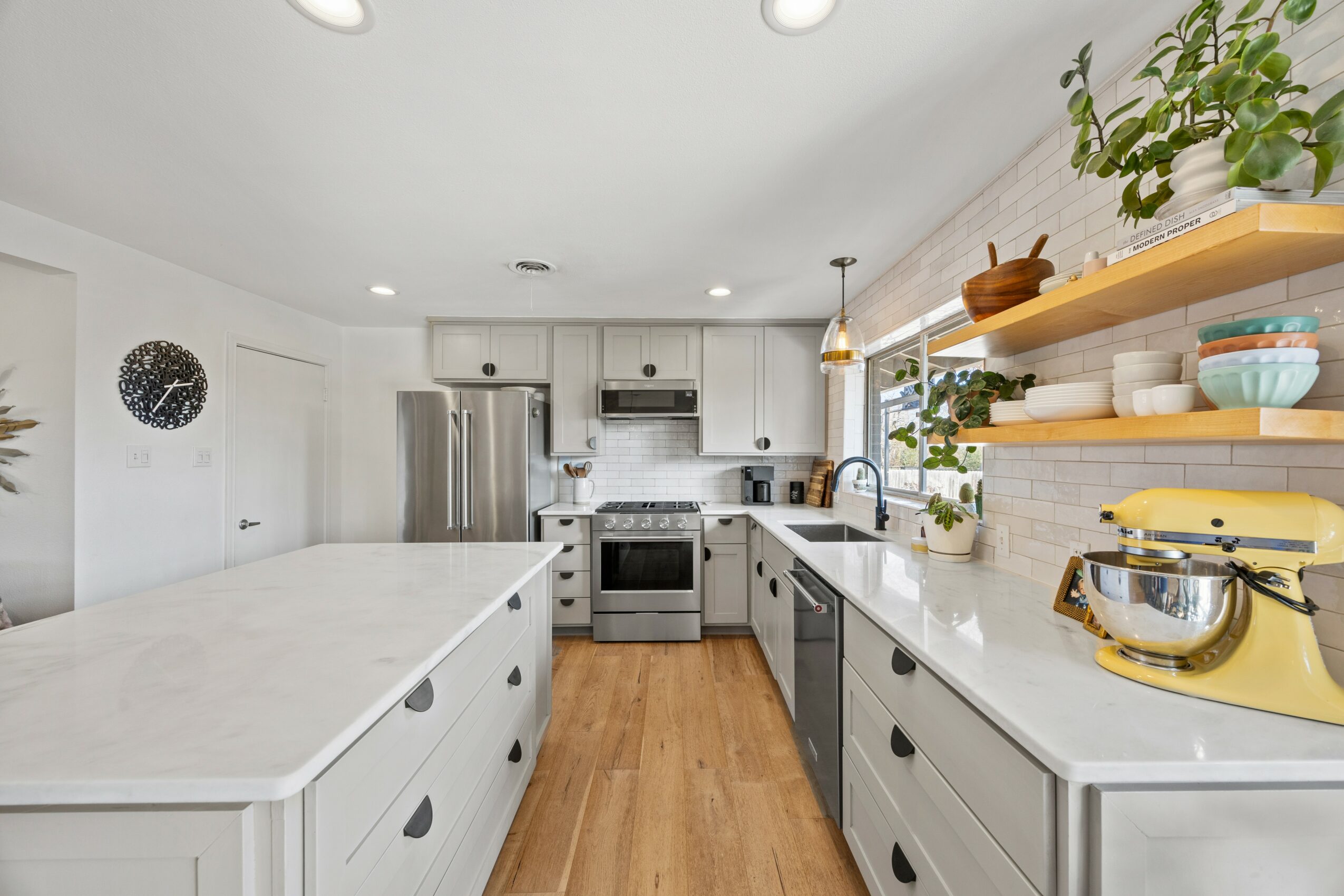 Modern kitchen with white cabinets, stainless steel appliances, and a large island with a marble countertop, bright and airy space.
