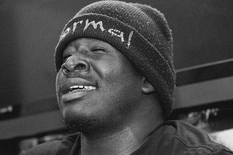 Person wearing a beanie with eyes closed and facial expression showing discomfort or pain.