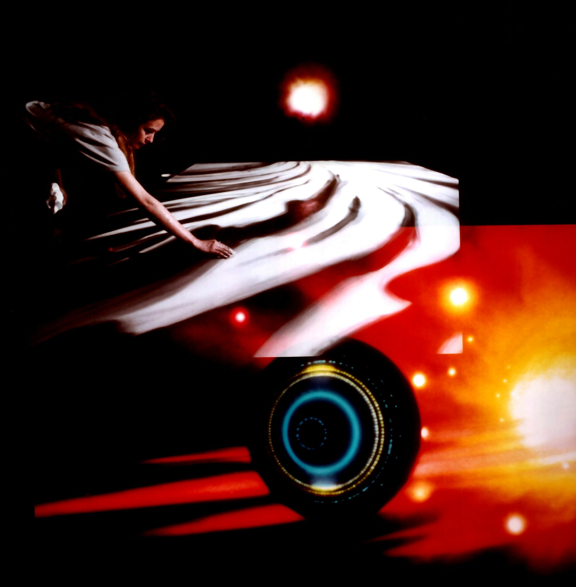 Person touching a flowing white fabric with a cosmic background, including planets and bright lights, in a dark setting.