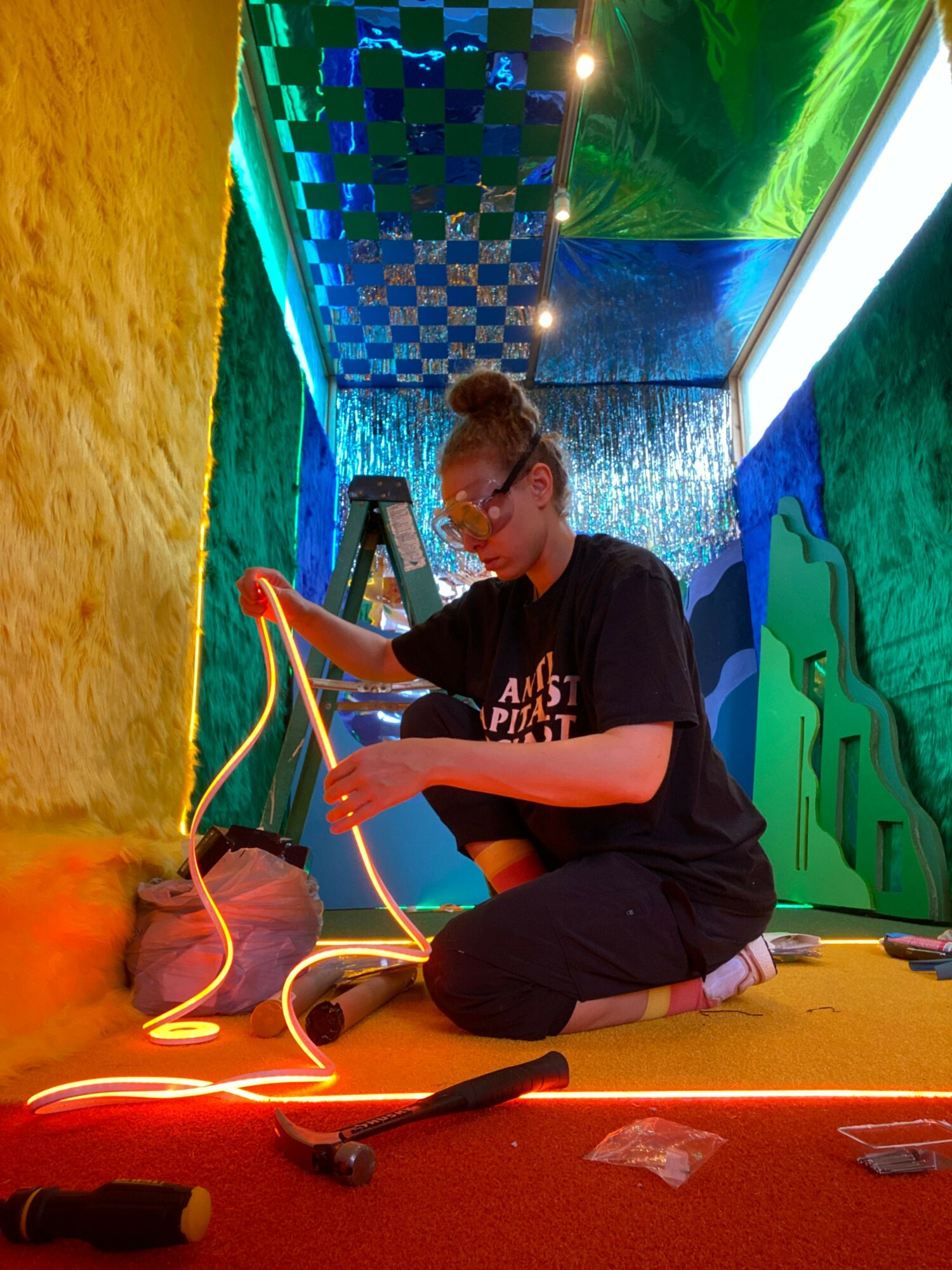 Person sitting on a colorful floor, using a device connected to wires, with a vibrant, patterned background.