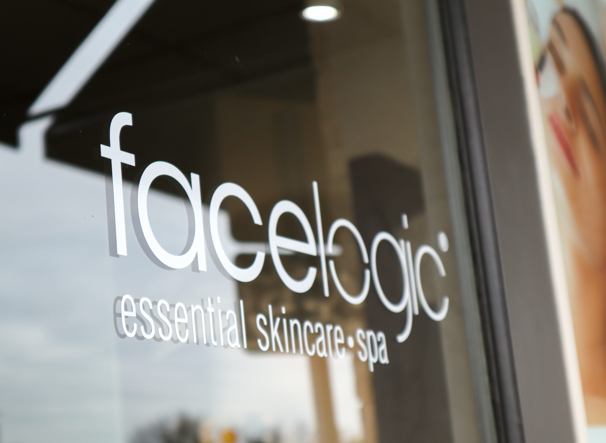 Glass window with white text reading 'facelogic essential skincare spa'.