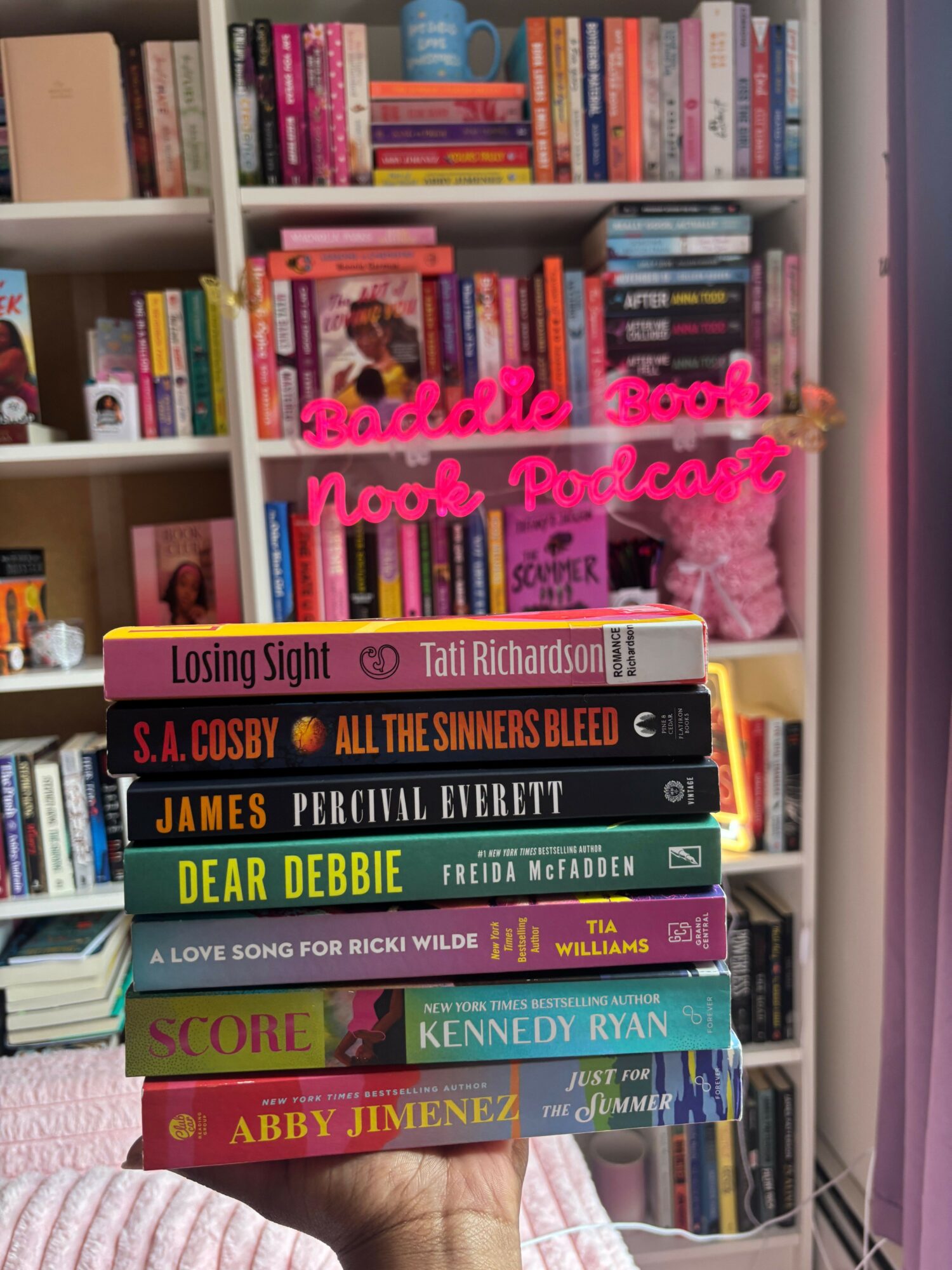 Bookshelves filled with colorful books, with pink handwritten text overlay reading 'Happy Reading!' and a pink decorative item.