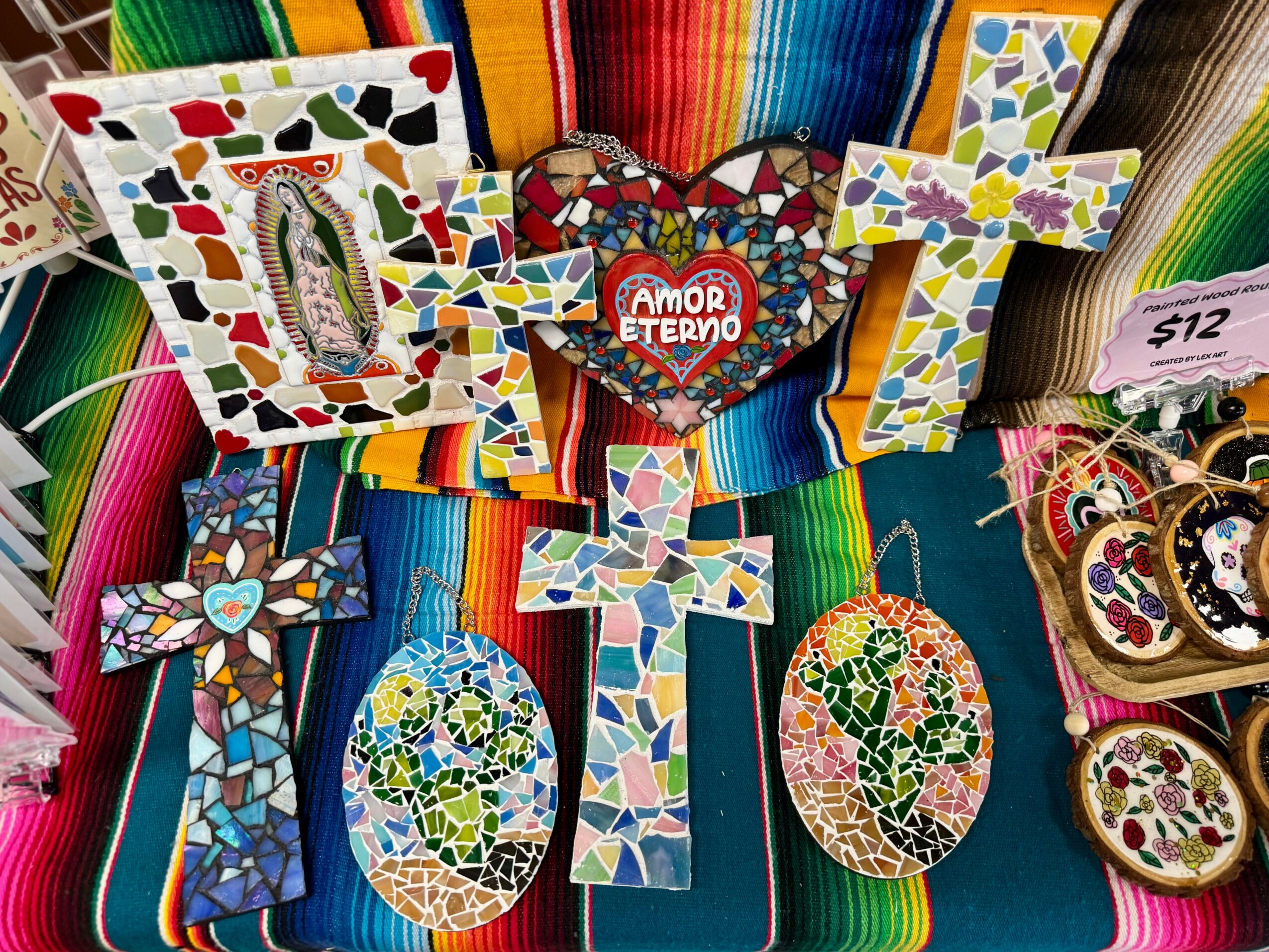 Colorful mosaic crosses and heart-shaped ornaments displayed on a vibrant striped fabric background.