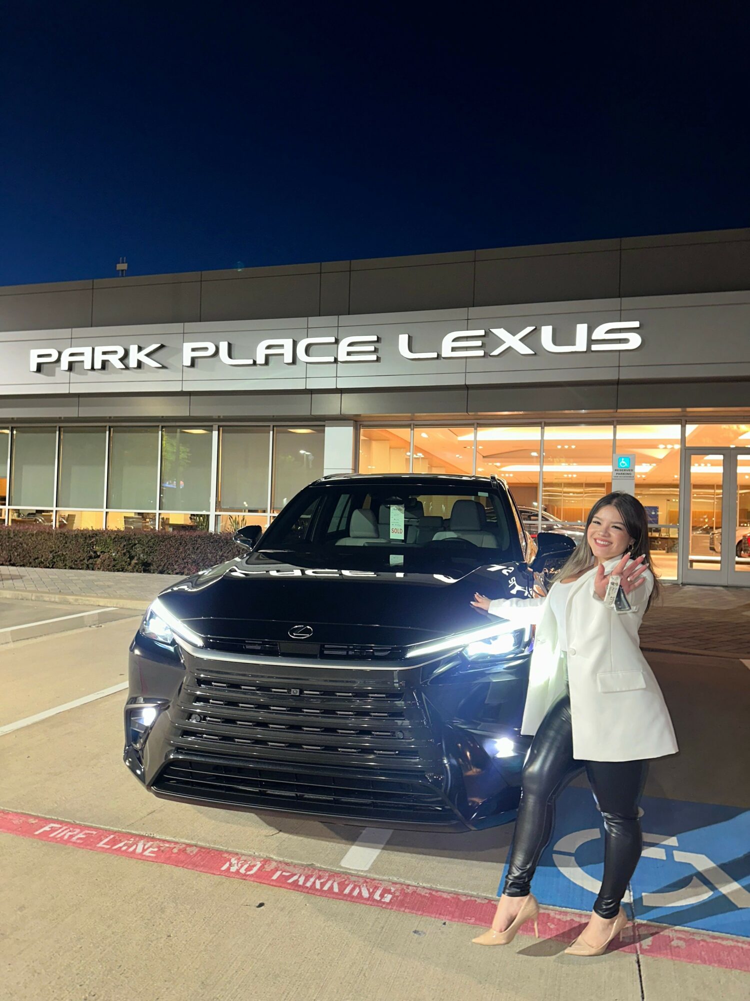 Person standing next to a black Lexus vehicle at a dealership, with a sign reading 'PARK PLACE LEXUS' in the background.