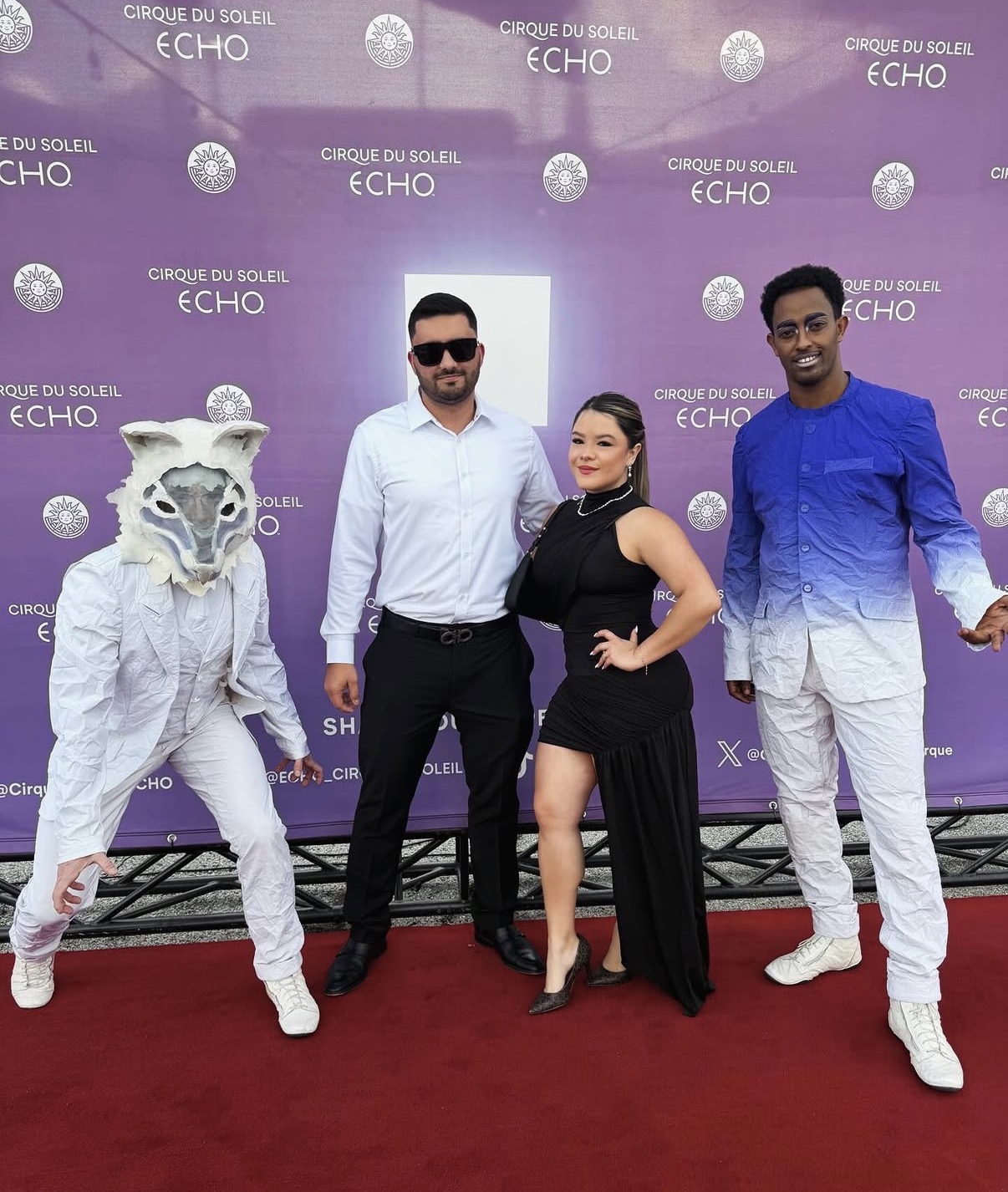 Four people and a person in a wolf costume pose on a red carpet in front of a purple backdrop with 'ECHO' and 'Cirque du Soleil' logos.
