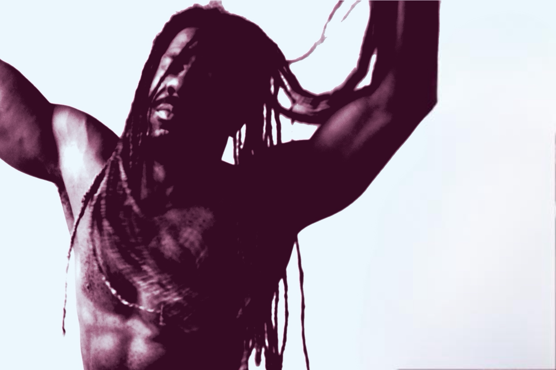 Person with long hair and muscular arms raising arms, facing sideways, with a light background.