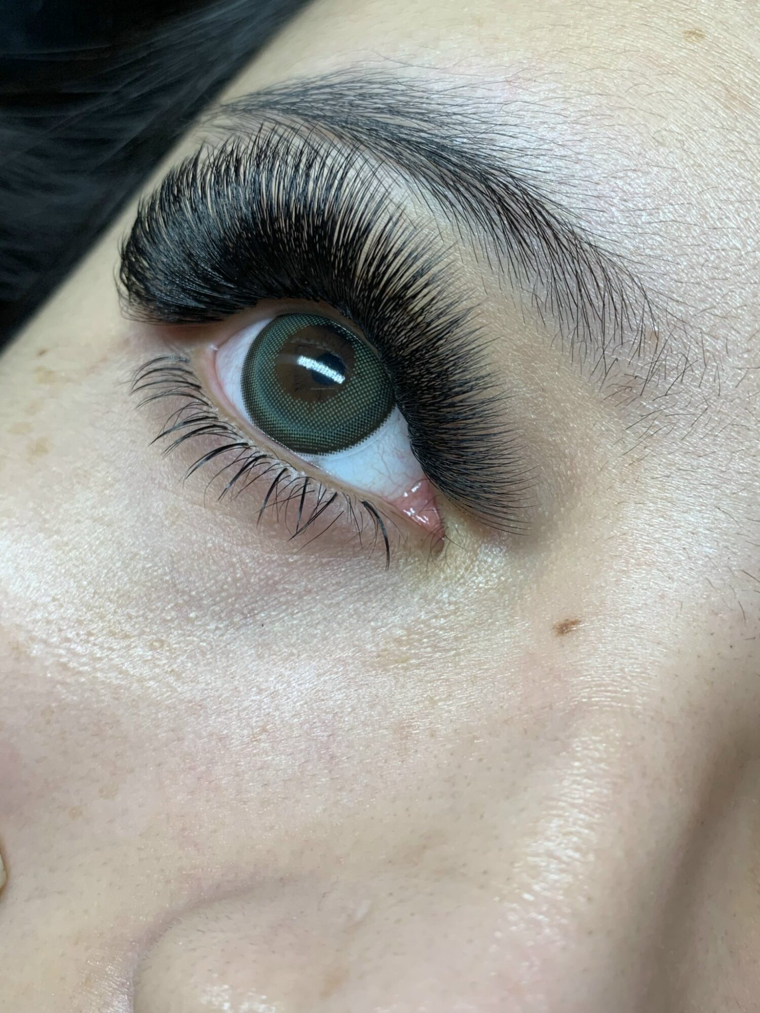 Close-up of a person's eye with long, thick eyelashes and a blue-green iris.