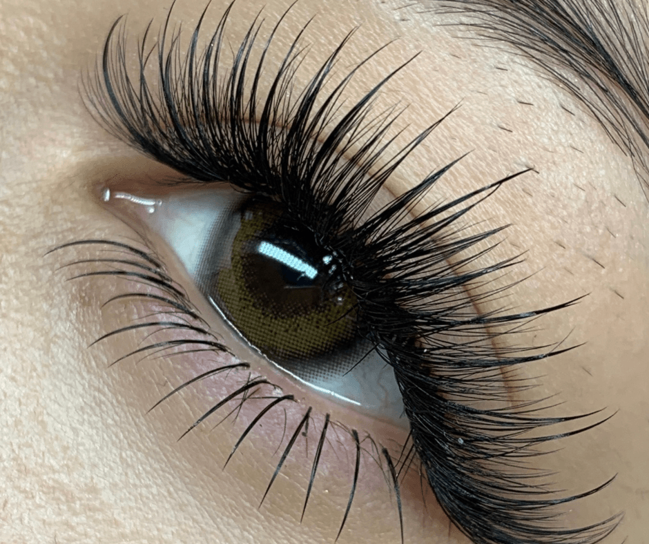 Close-up of a person's eye with long, thick eyelashes and brown iris, looking slightly upward.
