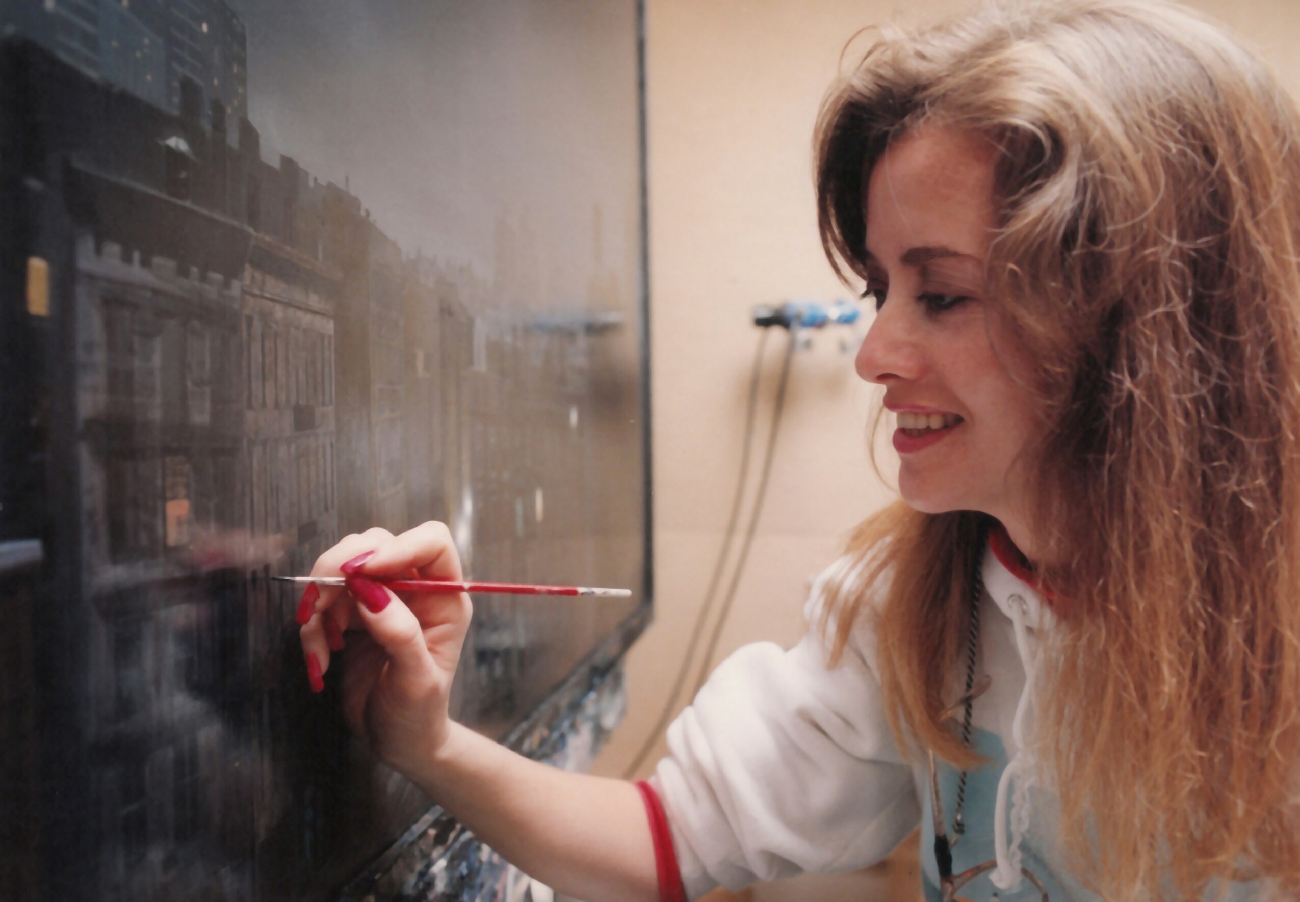 Woman writing on a blackboard with chalk, smiling, in a classroom or similar setting.