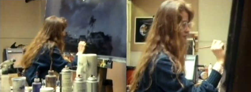 Woman with long hair working at a desk with bottles and a window behind her.