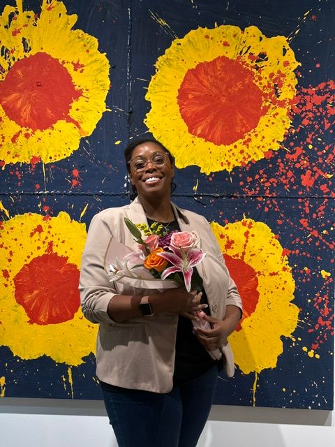 Woman holding a bouquet of flowers in front of a colorful abstract background with yellow and red splashes.