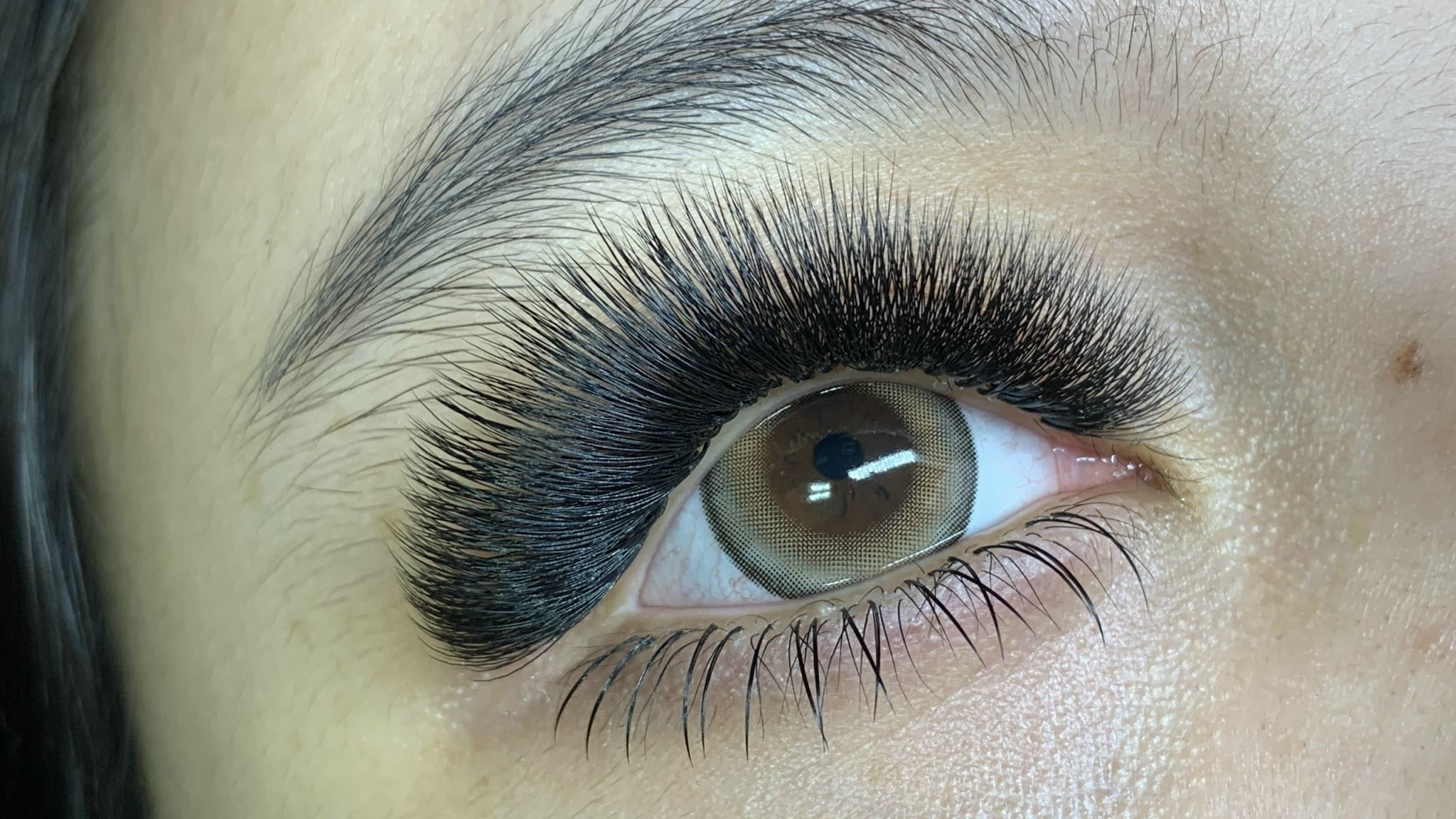 Close-up of a person's eye with long, thick eyelashes and a visible brown iris.