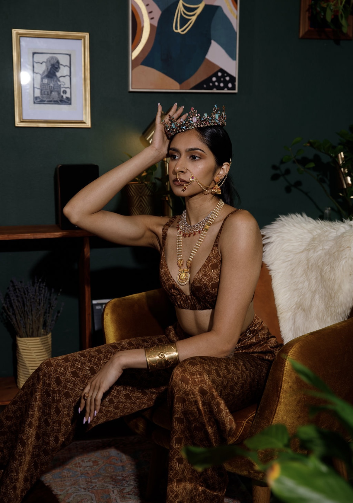 Woman in leopard print outfit with jewelry, sitting on a chair, holding her head, in a decorated room.