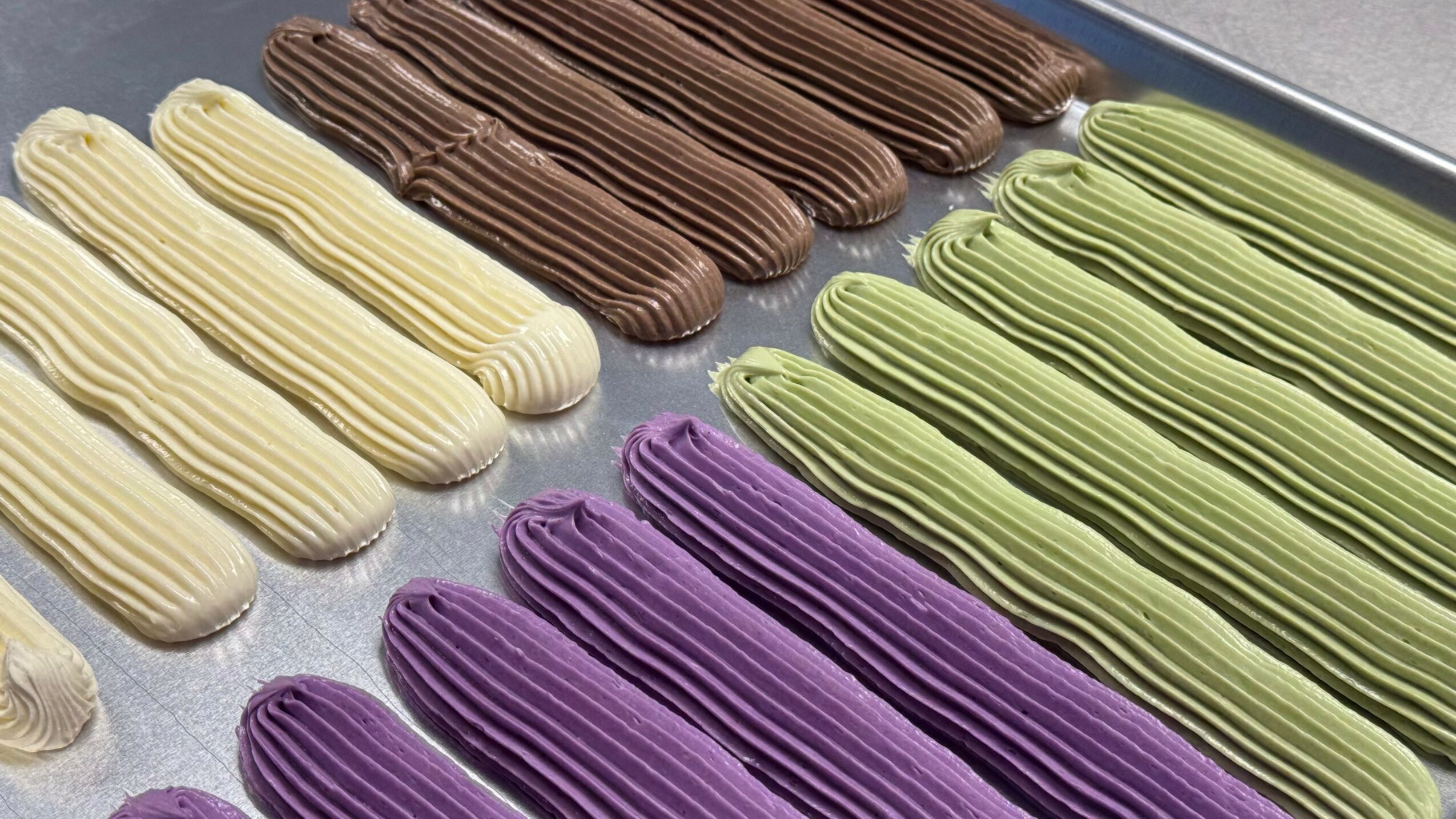 Colorful elongated candies arranged in rows on a tray, including white, brown, green, and purple candies.