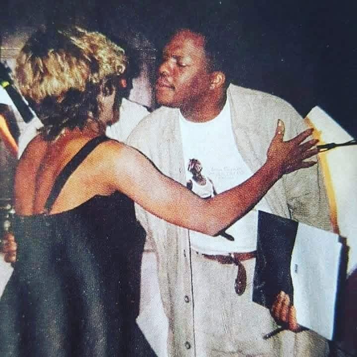 Two people facing each other, one with short curly hair and the other with short hair, engaging in conversation or interaction.