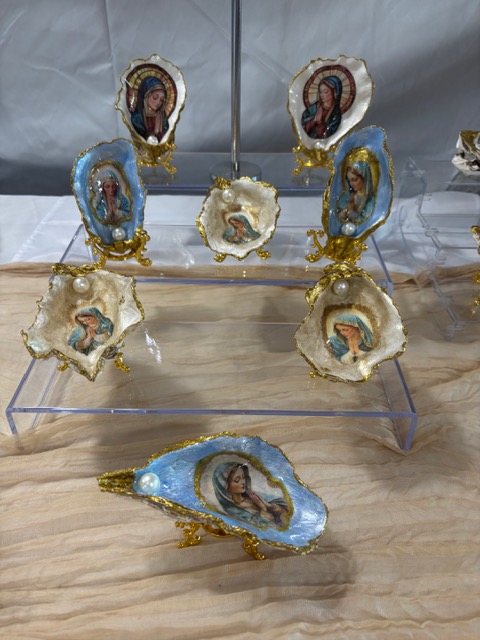 Collection of decorative porcelain shells with gold accents, displayed on a transparent stand and a wooden surface.