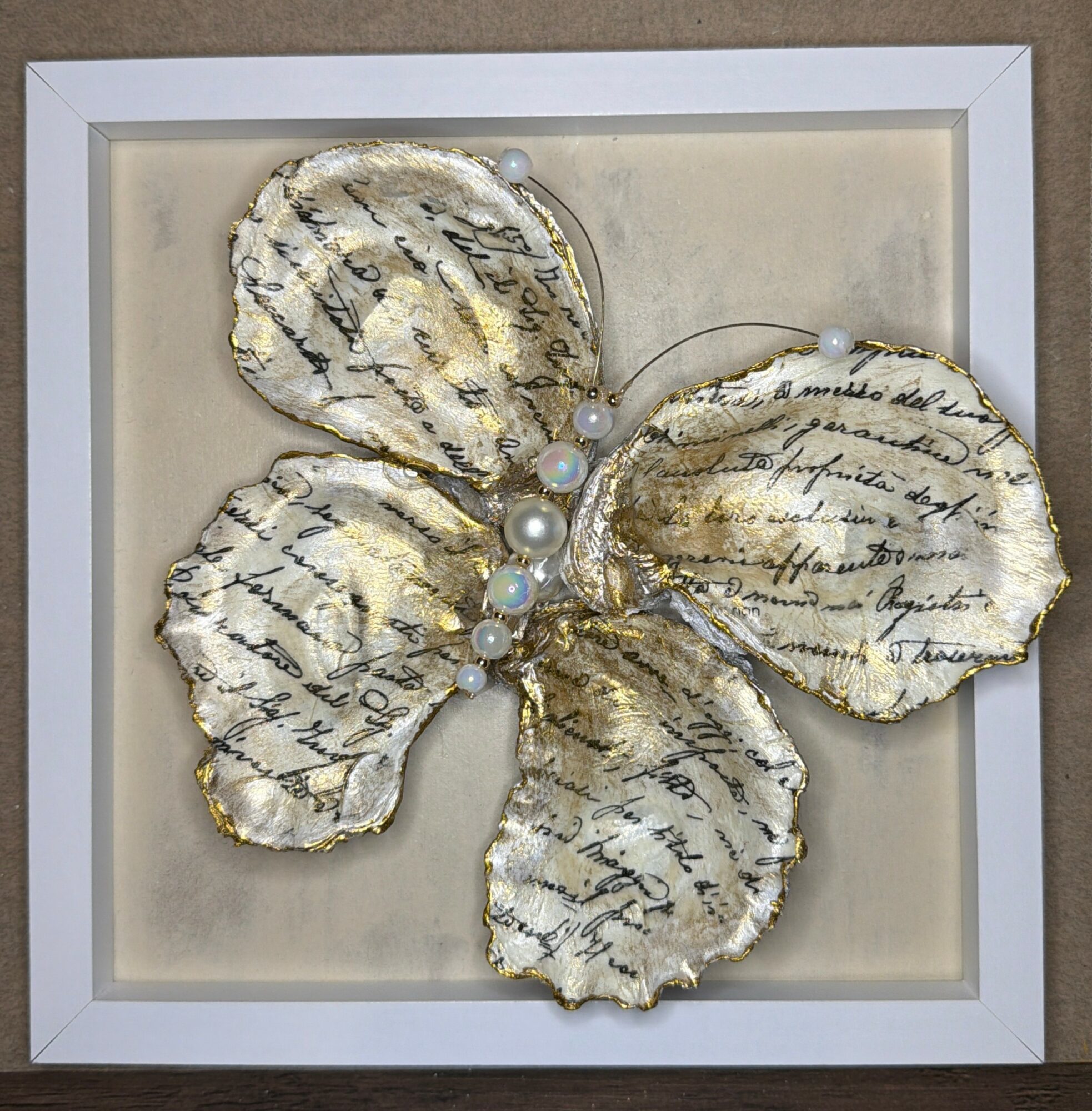 Decorative butterfly with gold edges and handwritten script on its wings, framed in a white square frame.