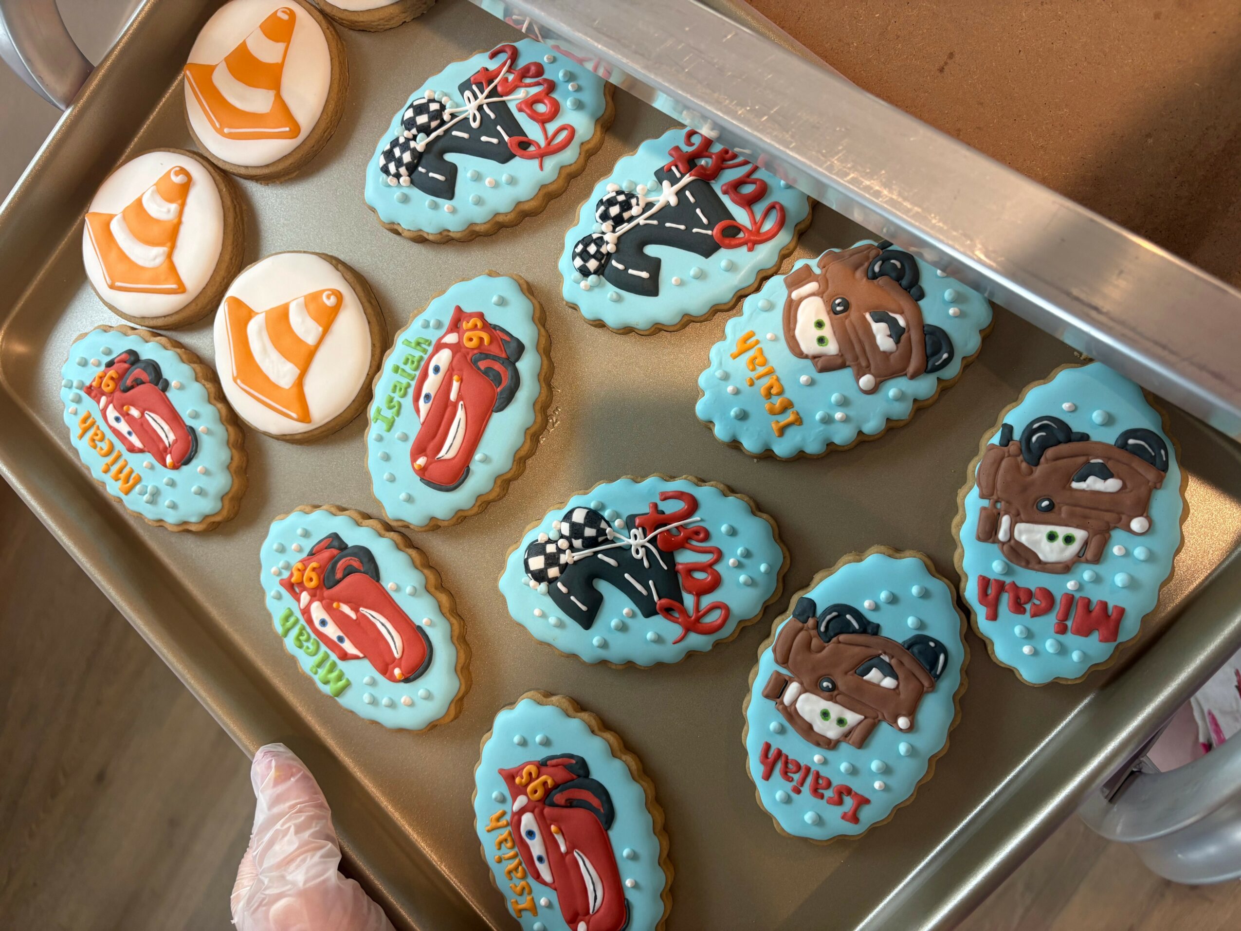 Tray of decorated cookies with various designs, including fish, cartoon characters, and abstract patterns, on a baking sheet.