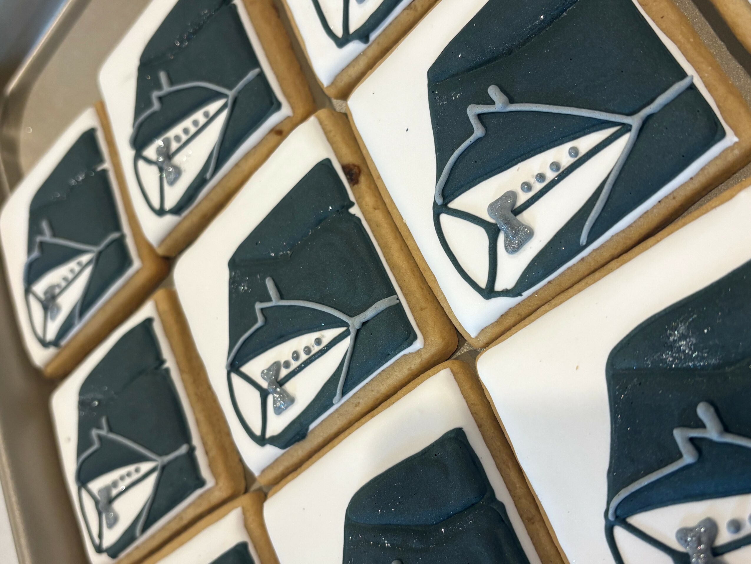 Cookies decorated with sailboat designs on white icing, arranged in a grid pattern.
