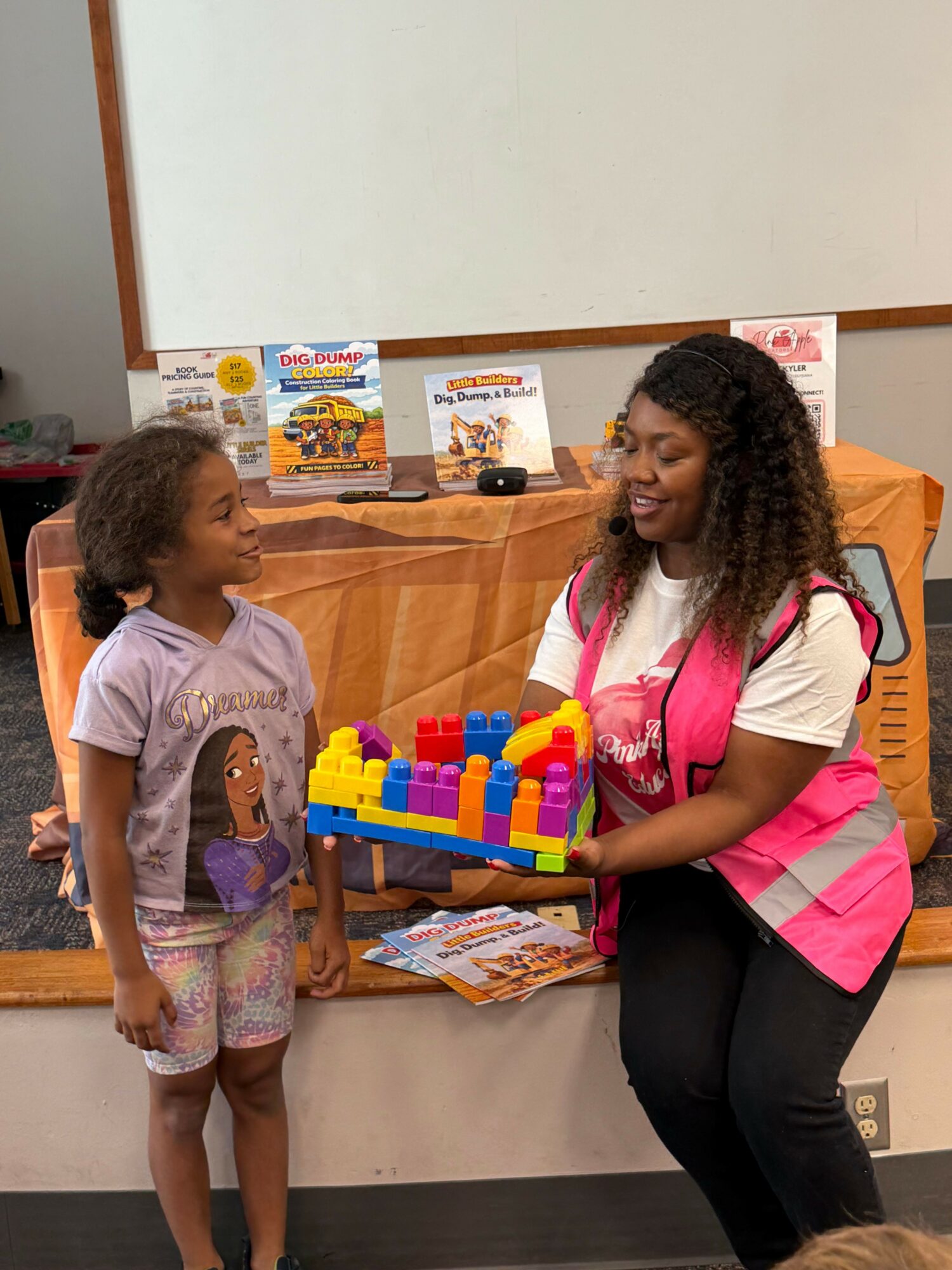 Adult woman and young girl interacting with a colorful toy on a wooden table in a room.