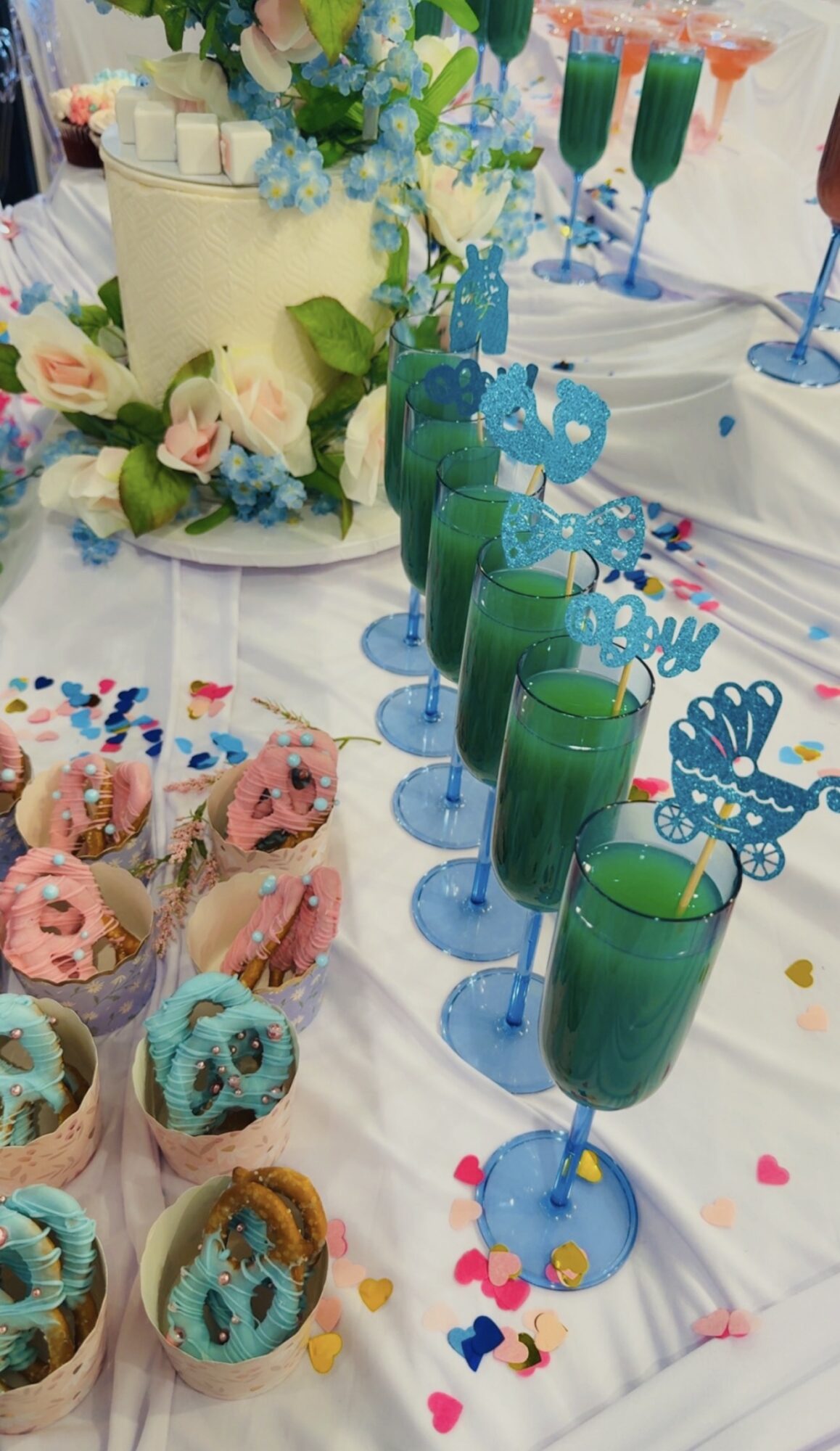 Colorful birthday table with cupcakes, drinks, and a cake decorated with flowers and butterflies, celebrating a birthday.