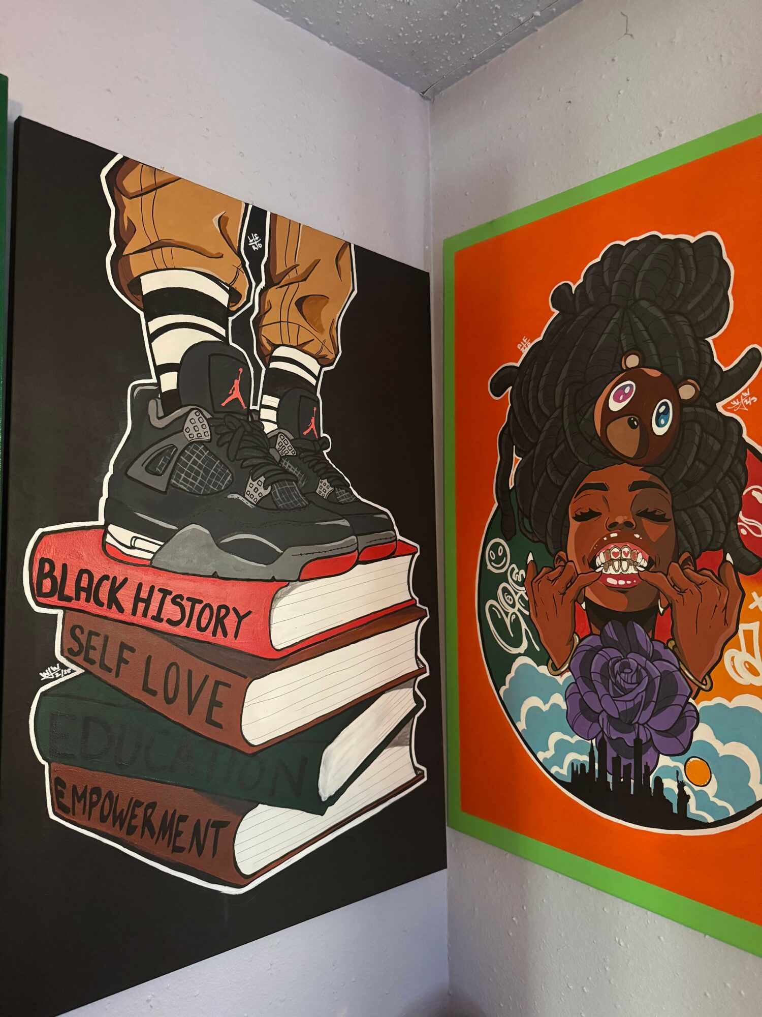 Two pairs of legs wearing sneakers and jeans, with books stacked behind them, titled 'Black History Self Love' and 'Unbreakable'.
