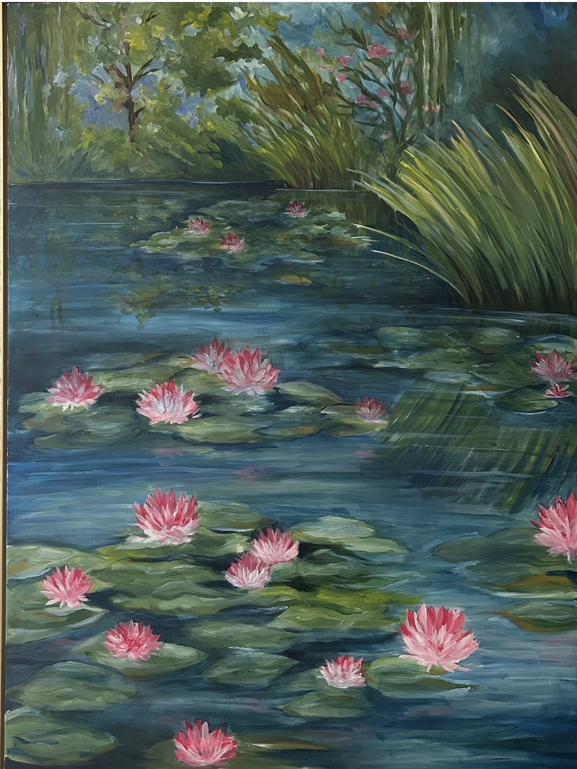 Water lilies with pink flowers floating on a pond surrounded by green plants and trees.