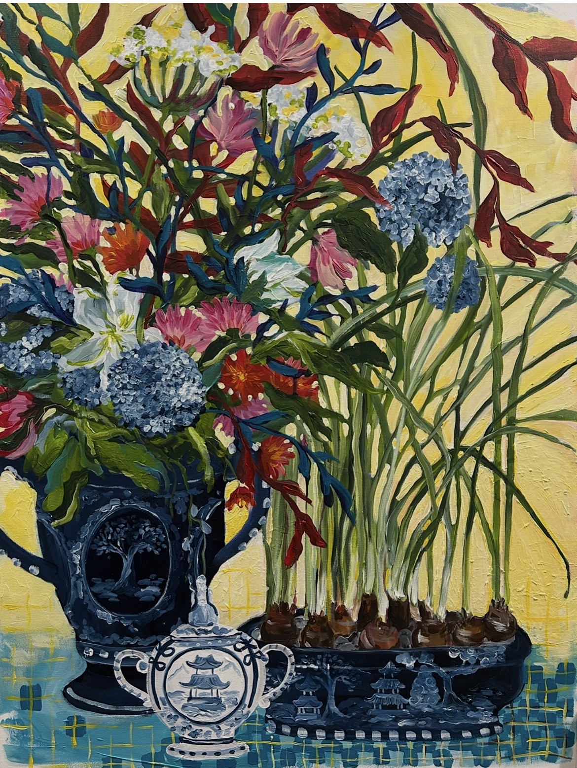 Vase with colorful flowers, including pink, blue, and red, on a yellow background with a blue patterned surface.