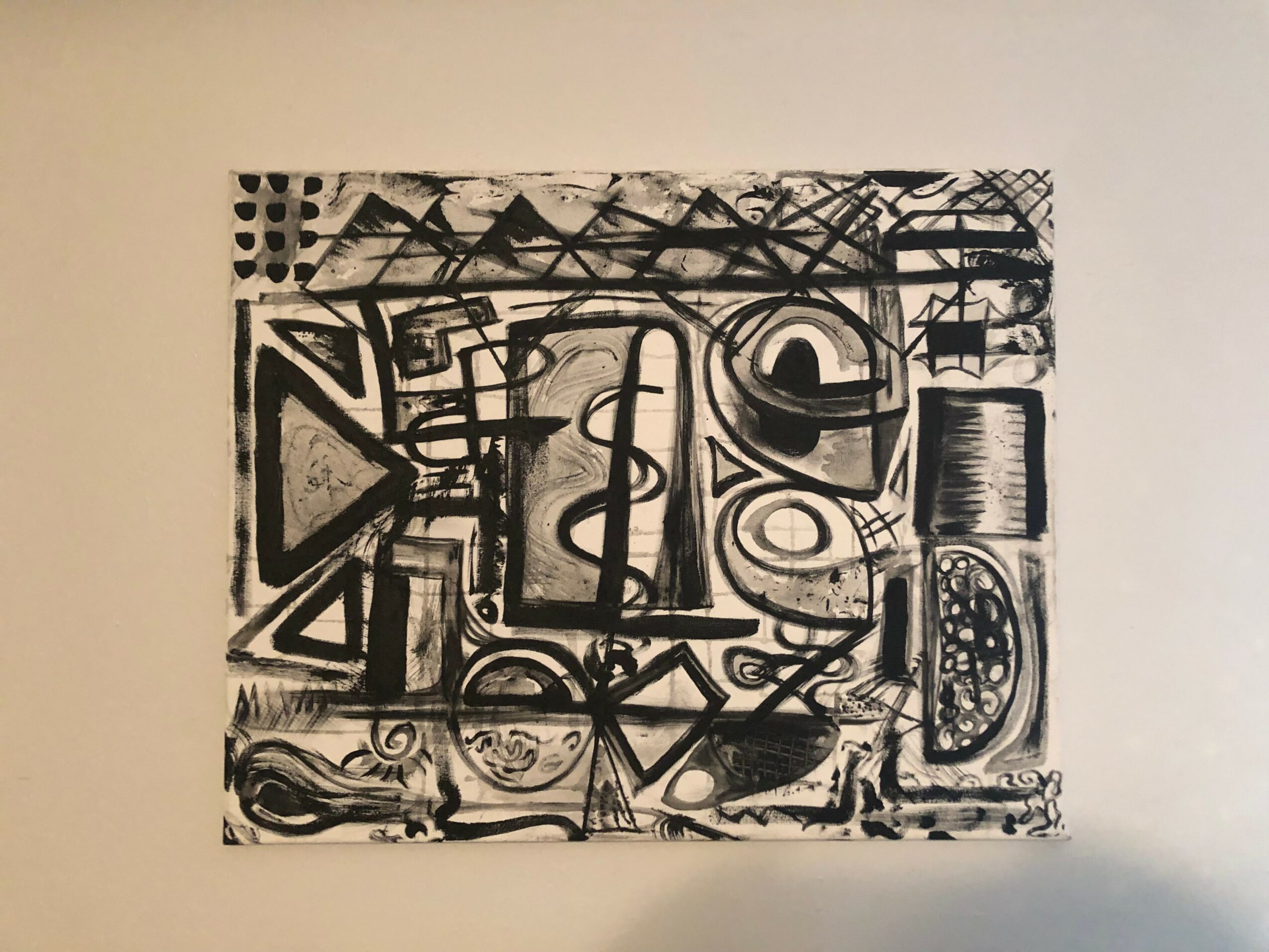 Abstract black and white artwork with geometric shapes and lines on a wall.