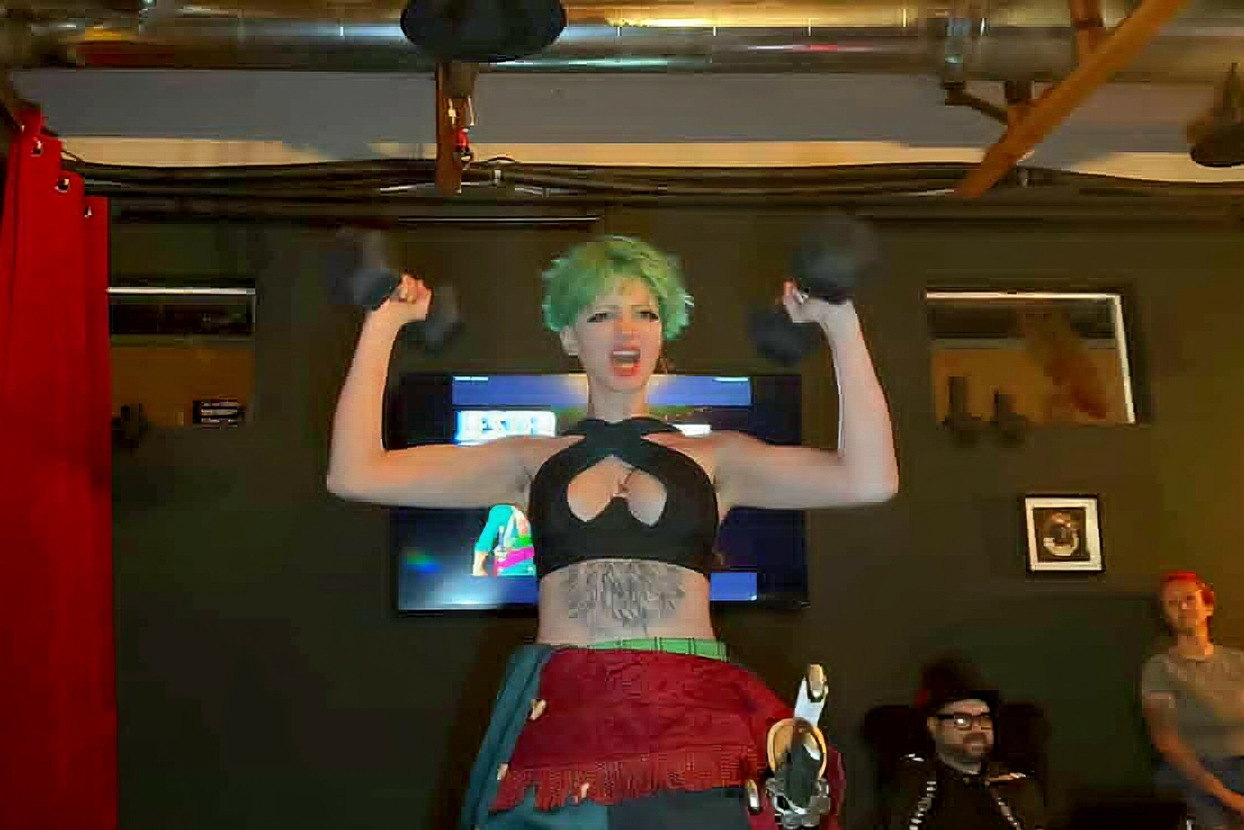 Person with green hair smiling and flexing arms, wearing a black top and red skirt, in a room with a TV and people.