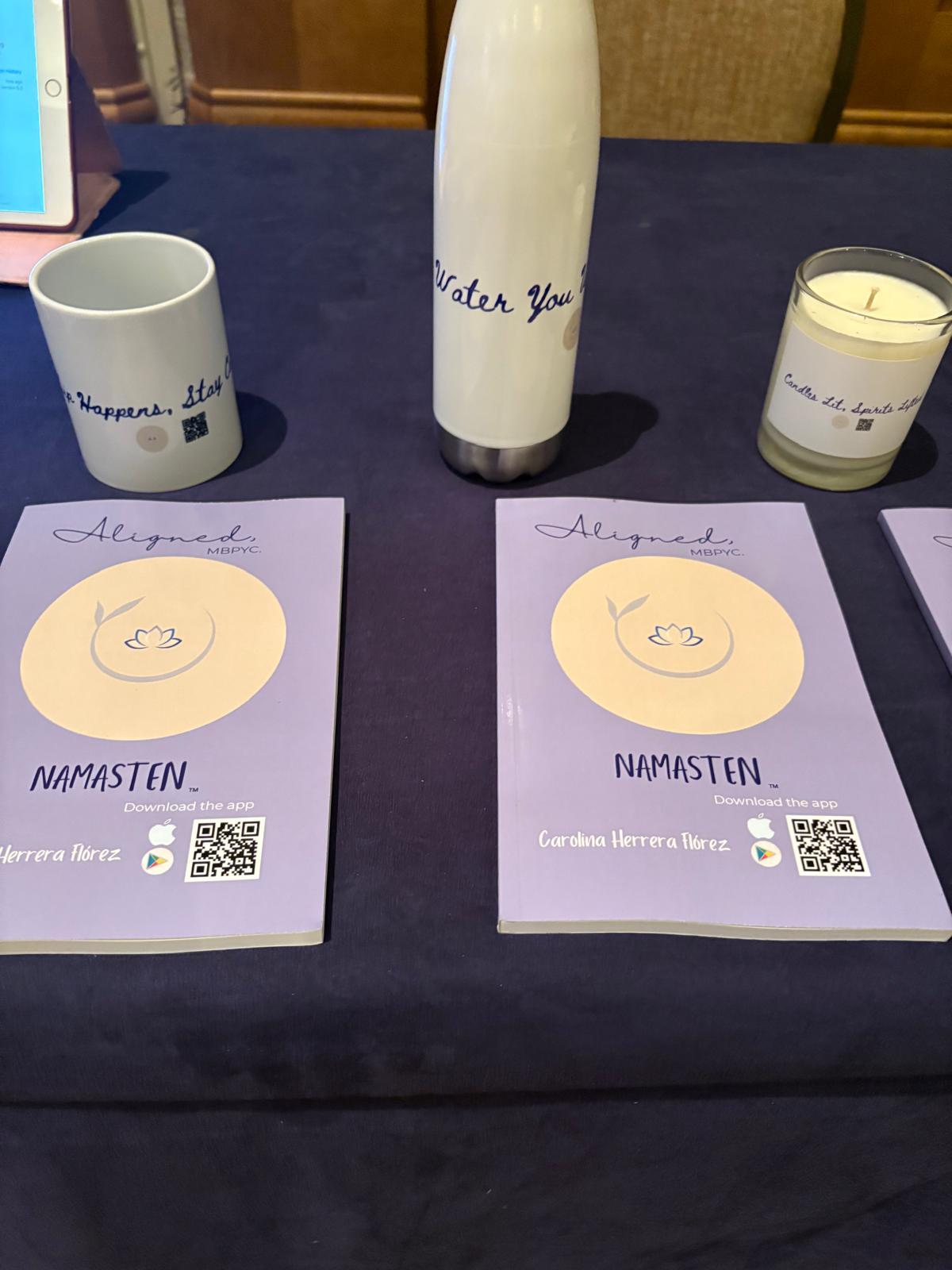 Two purple flyers with yellow circles and handwritten text, a white mug, a tall white bottle, and a candle on a dark table.