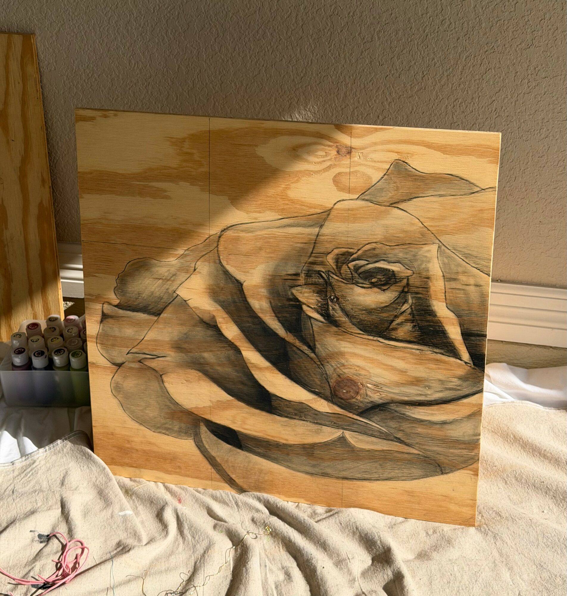 Wooden panel with a black and gray abstract line drawing of a person lying down, with a mountain in the background.
