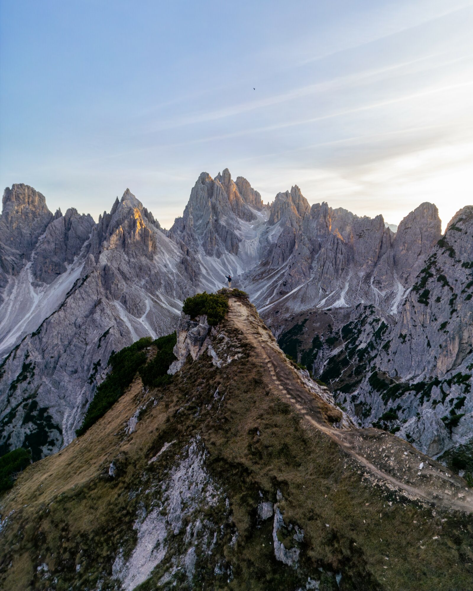 Mountain range with rugged peaks under a clear sky, with a grassy ridge in the foreground.