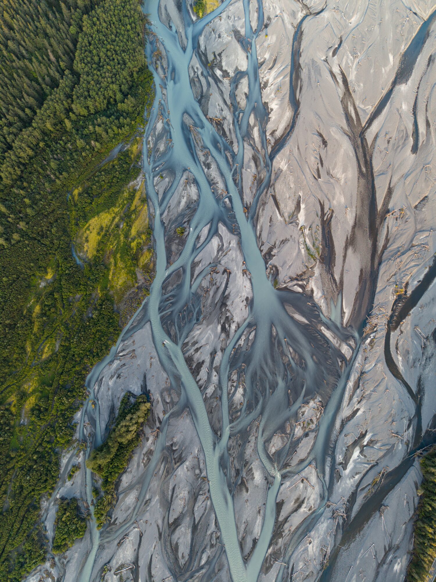 Aerial view of a river with multiple channels flowing through rocky terrain and green forested area.