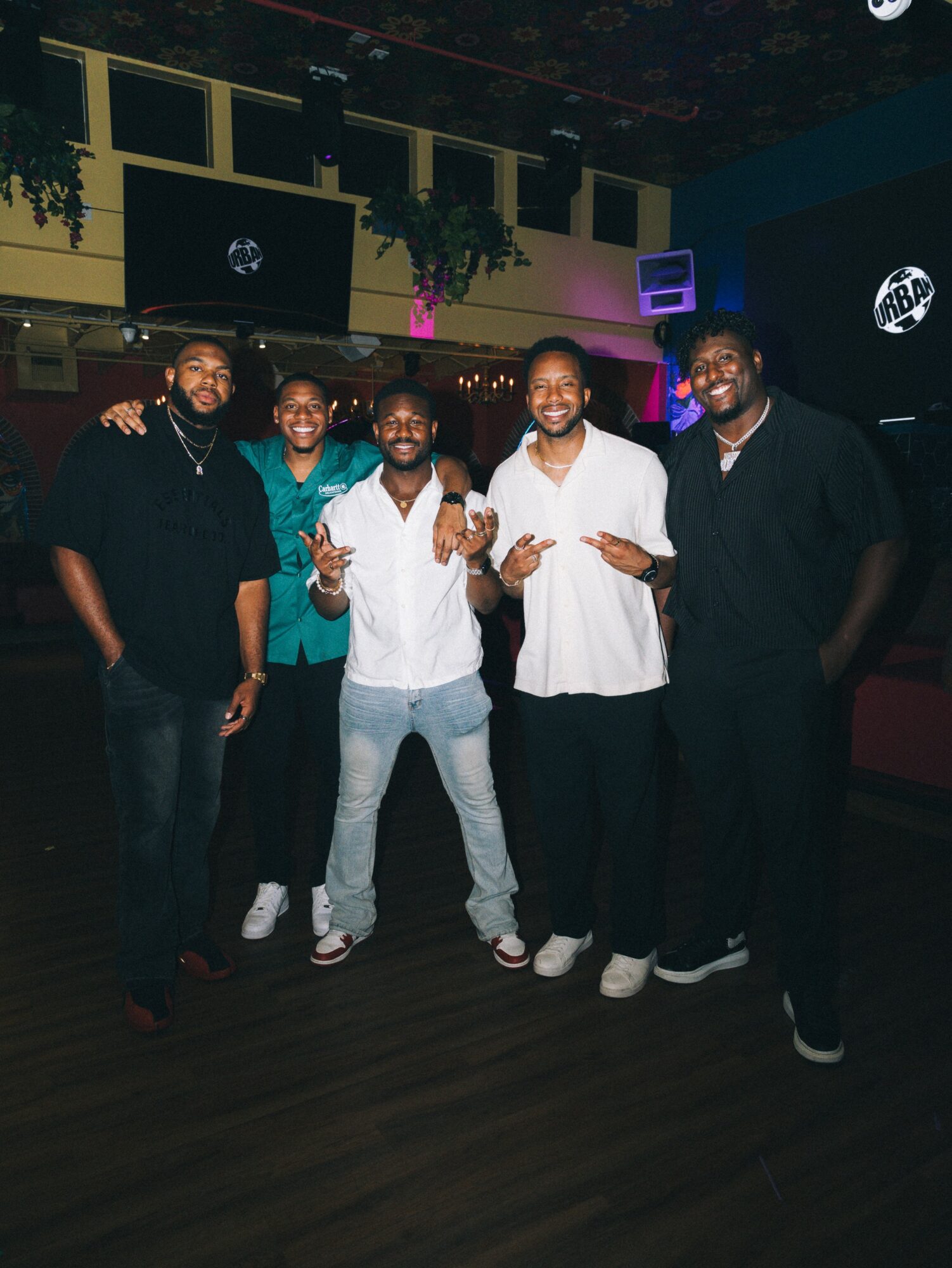 Five people standing together in a dimly lit indoor space, smiling and posing for the photo.