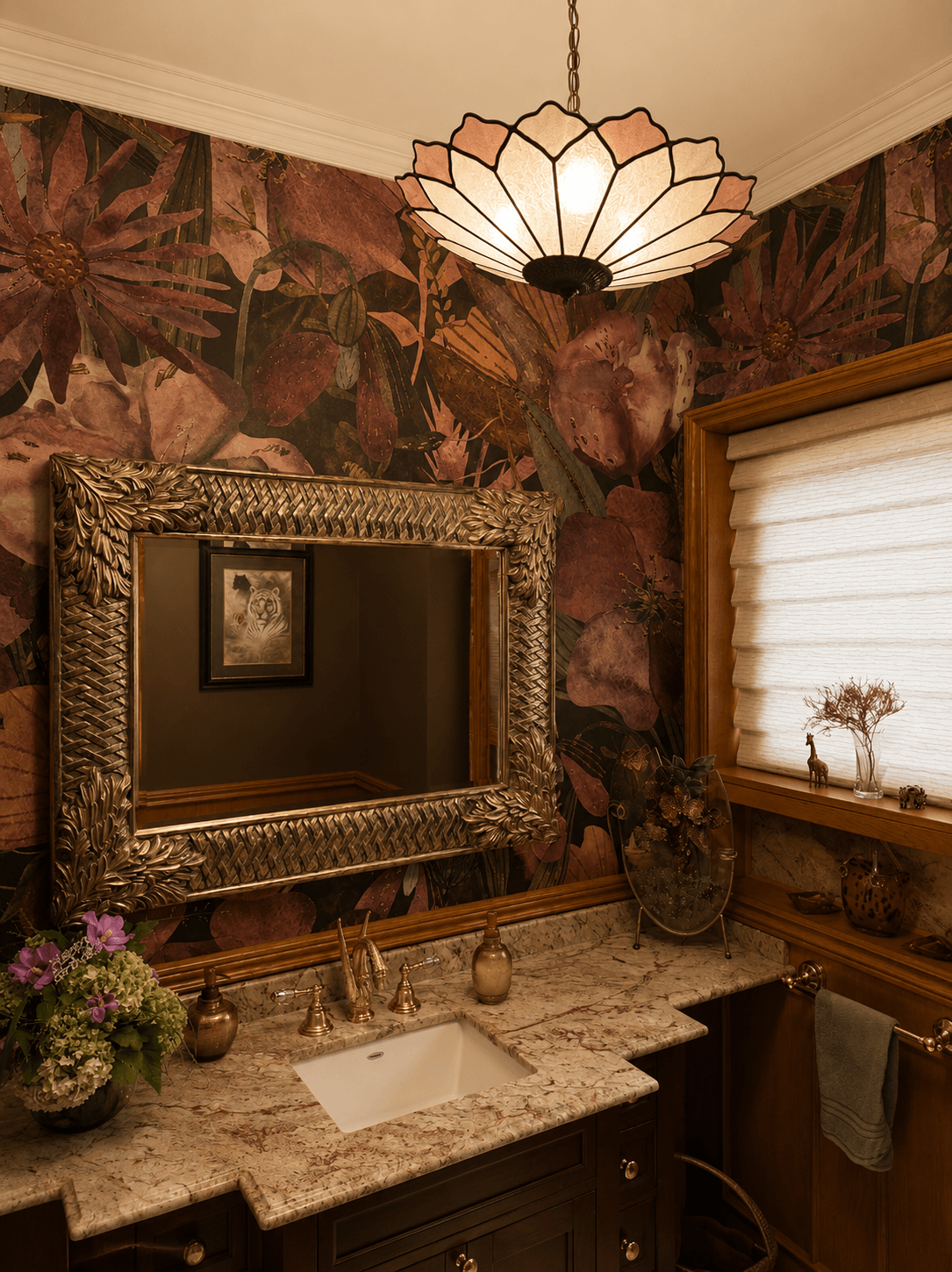 Bathroom with floral wallpaper, large ornate mirror, granite countertop, window with blinds, and decorative items.