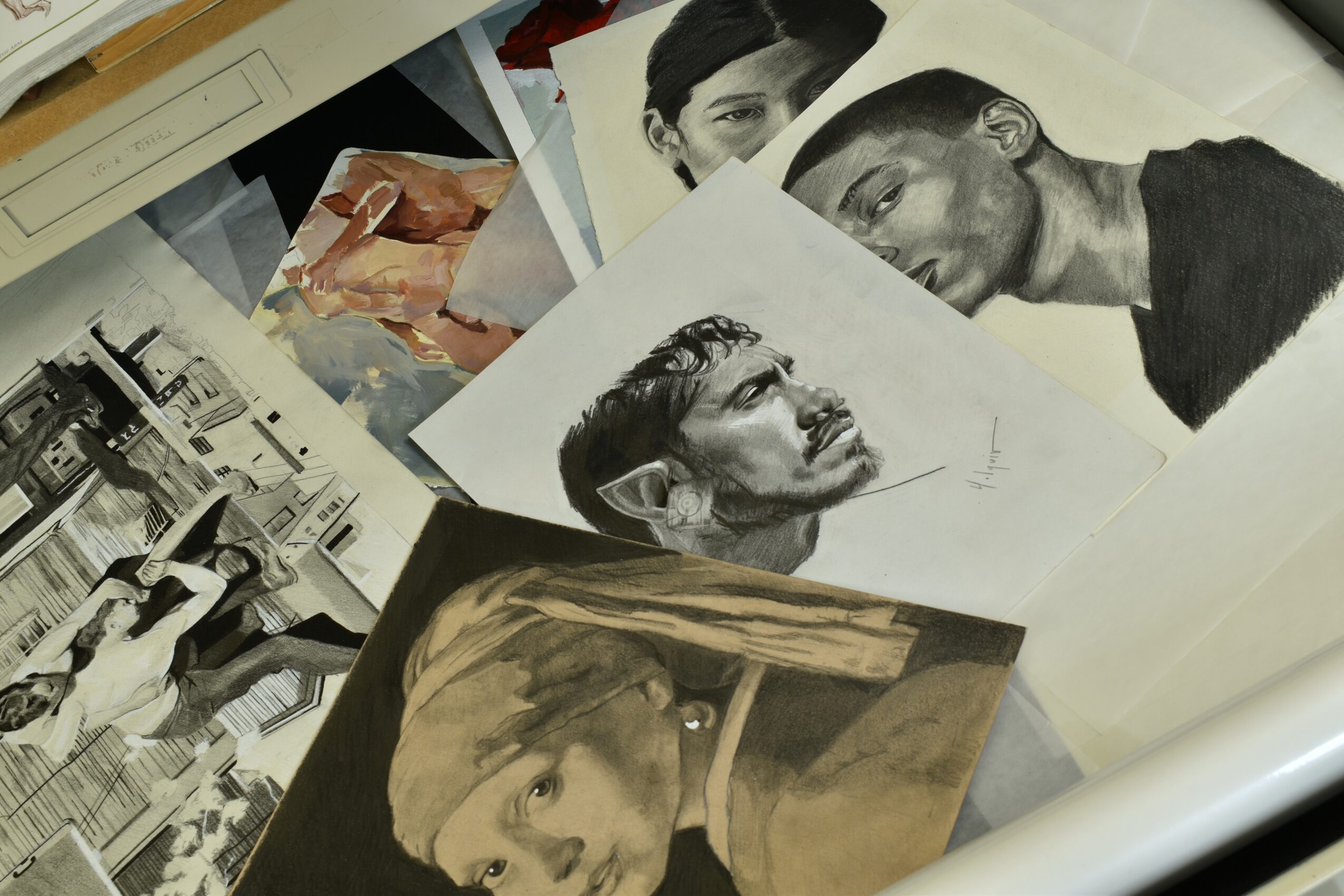 Collection of black and white and color portraits and sketches of people, scattered on a surface.