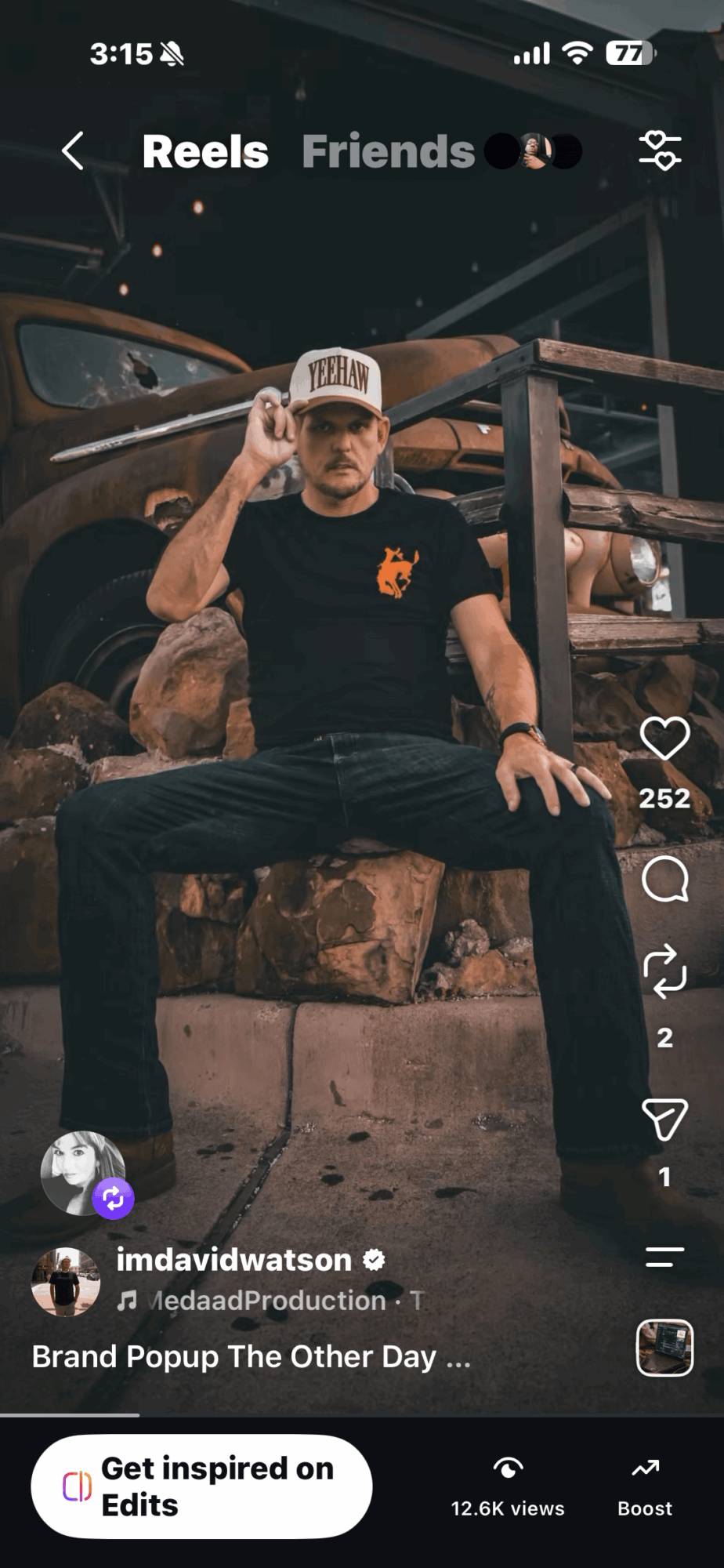 Person sitting on a stone ledge in a dark setting, wearing a cap and black clothing, with a hand near the face.