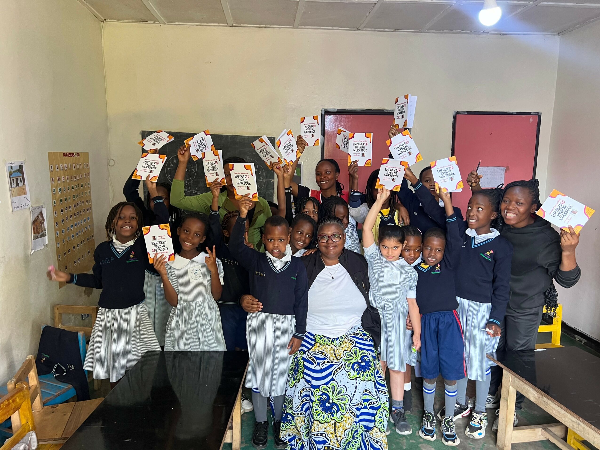 Group of children in school uniforms holding certificates, smiling in classroom with colorful walls and blackboard.
