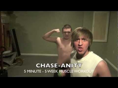 Two shirtless men in a room, one flexing arm, the other looking surprised, with text about muscle workout.