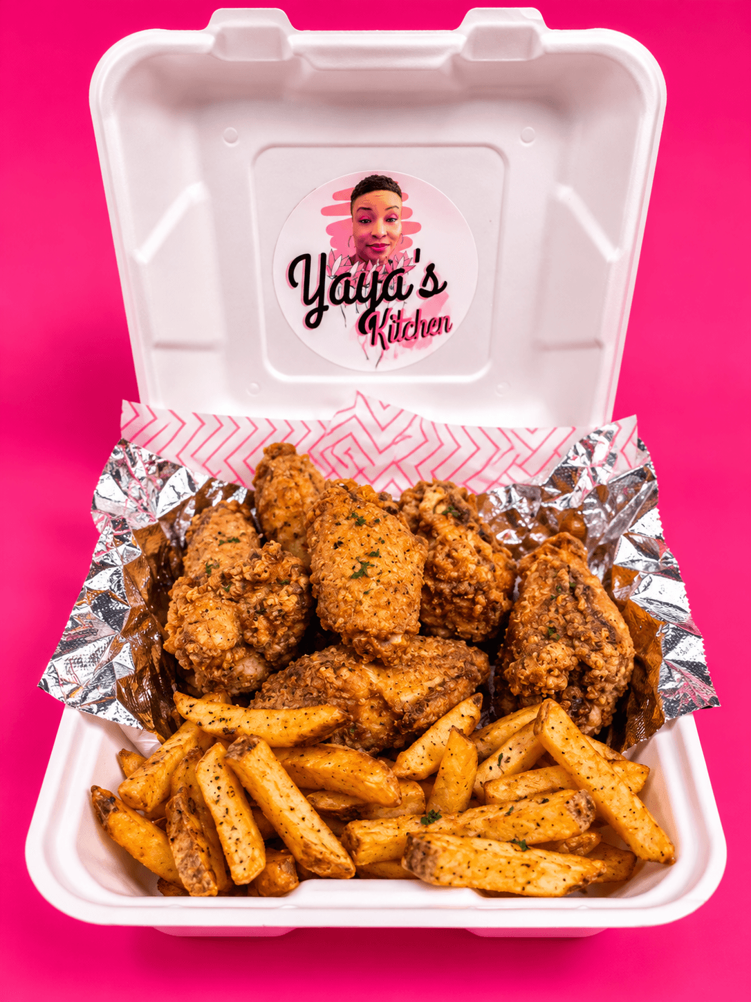 Open takeout box with fried chicken pieces and seasoned fries on foil, pink background, label with a cartoon girl and text.