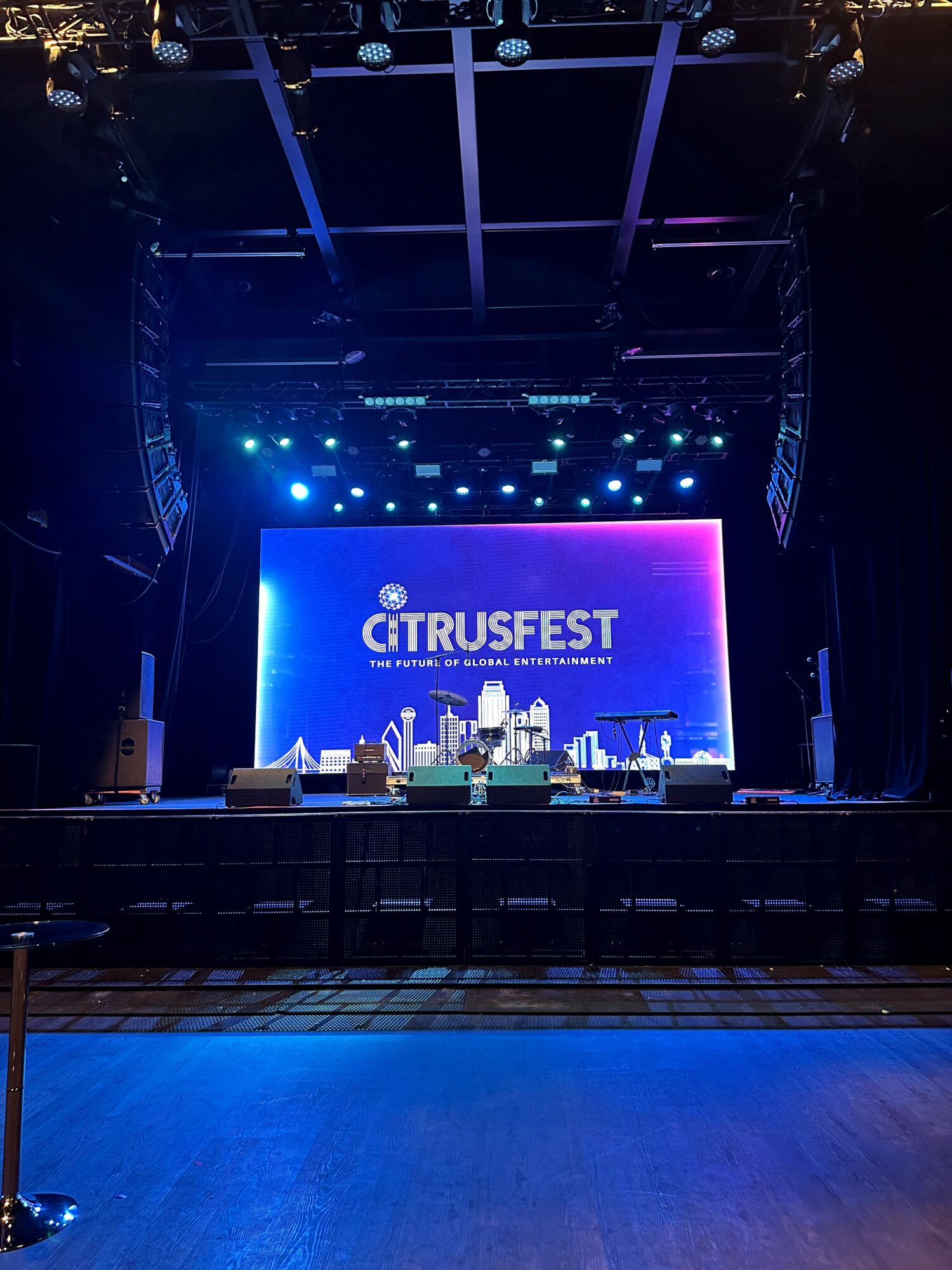 Stage with blue and purple lighting, large screen displaying 'CITRUSEST', and musical instruments set up.
