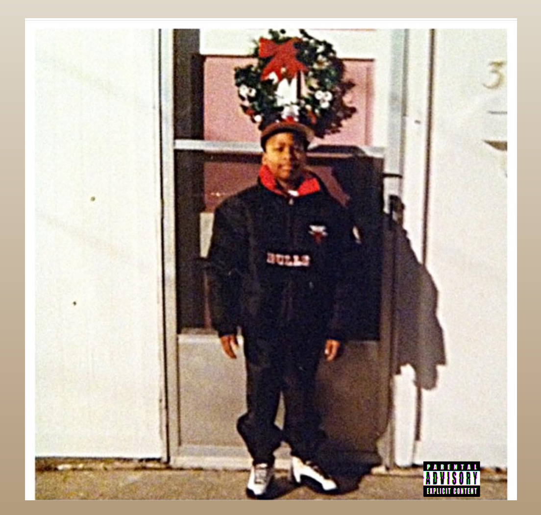 Child standing outside a door with a wreath above, wearing a black jacket, red hoodie, and sneakers.